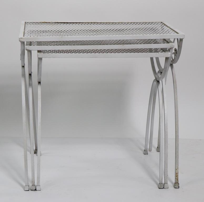 Chic and stylish set of three nesting tables of wrought iron with metal mesh tops. All three are in very good condition, clean and ready to use. Perfect for garden, patio, sunroom, or poolside application, manufacture attributed to Salterini.