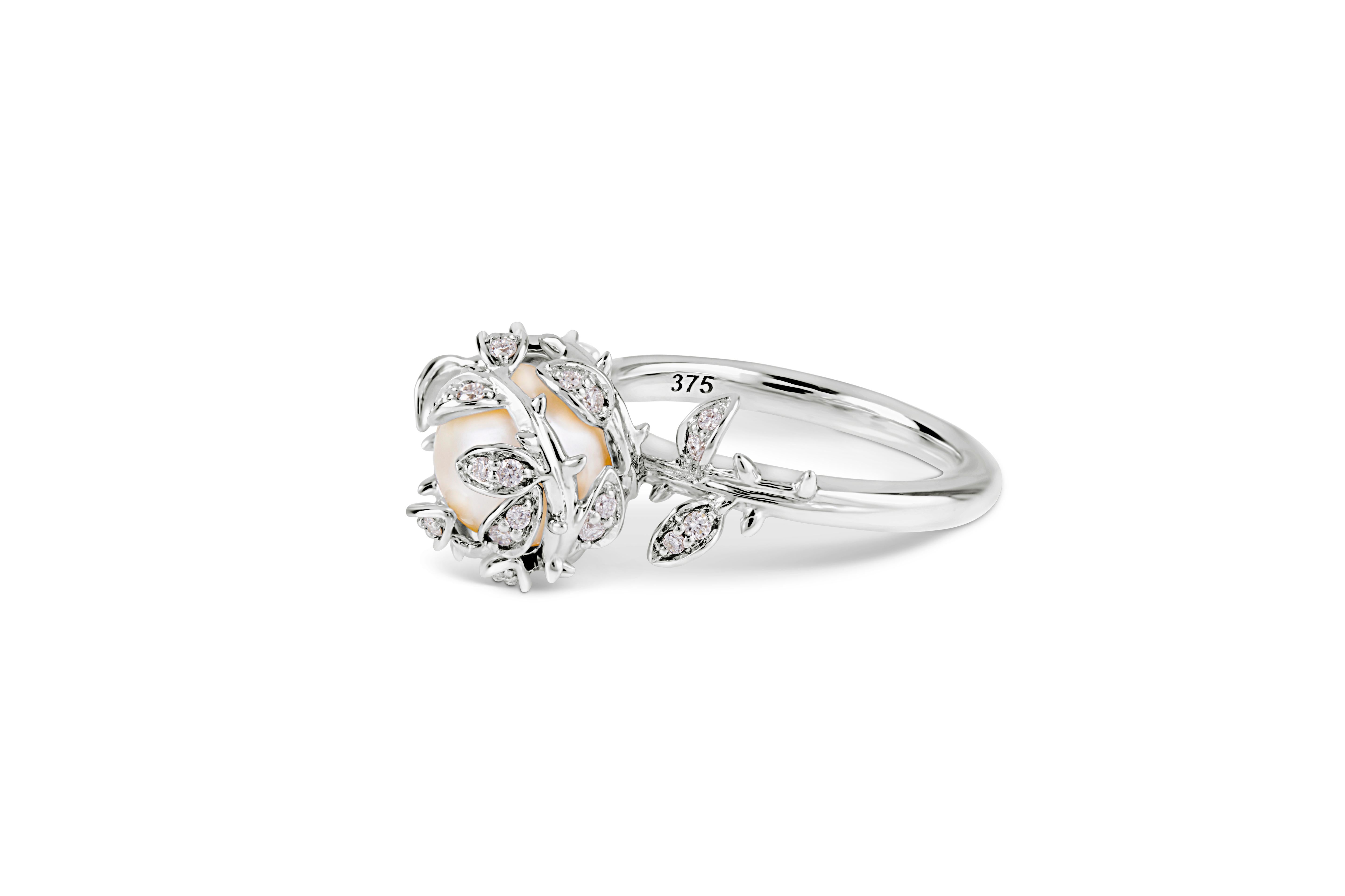 Cette bague habillée très détaillée présente une perle d'eau douce nichée parmi des feuilles de diamant et montée sur un anneau en or blanc 9ct. Notre bague à perles imbriquées représente les 