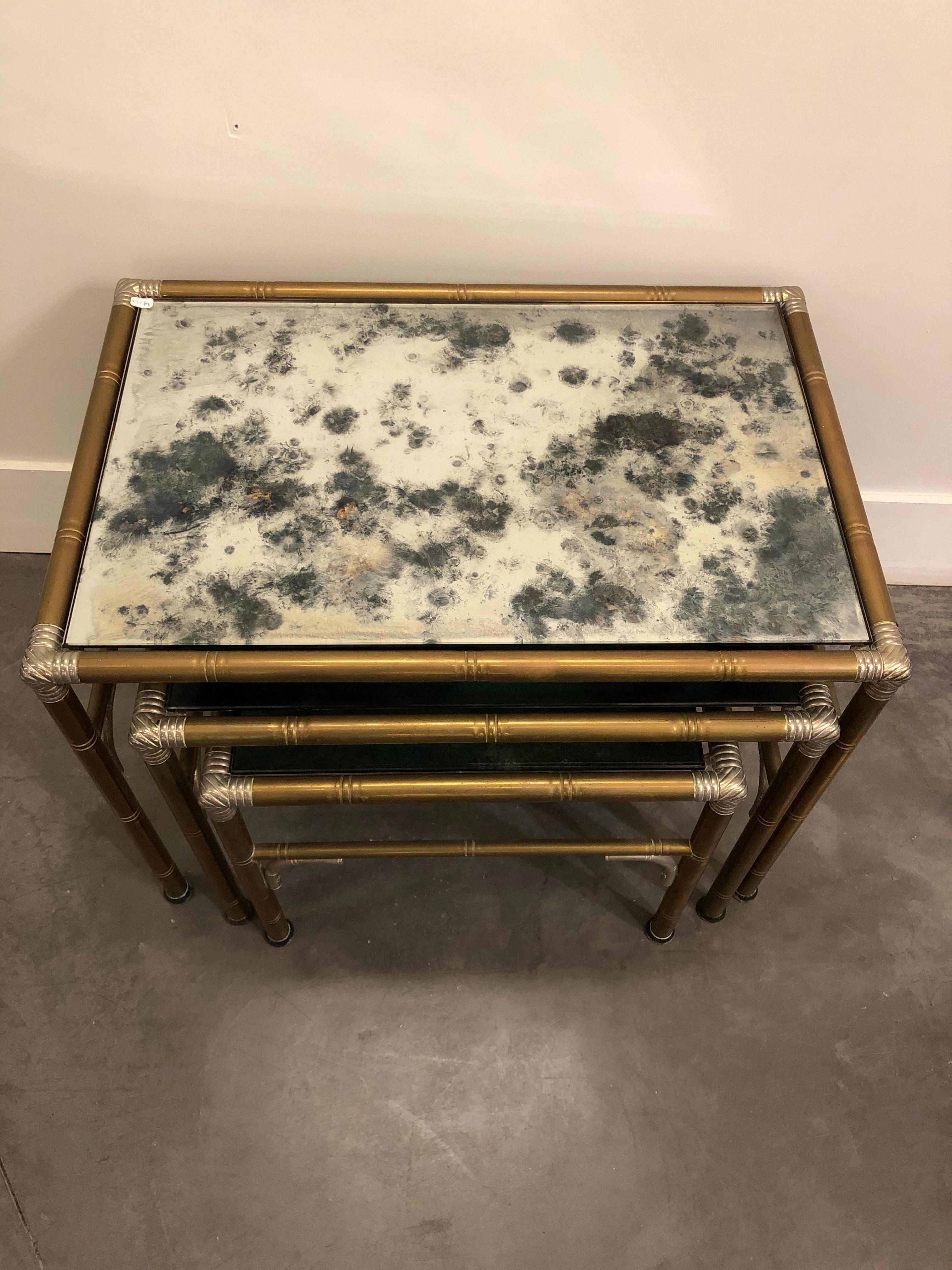 Set of 3 nesting tables in patinated metal and smoked glass finish.
Treated like bamboo joined and attached by a knot at each extremity of the square.
