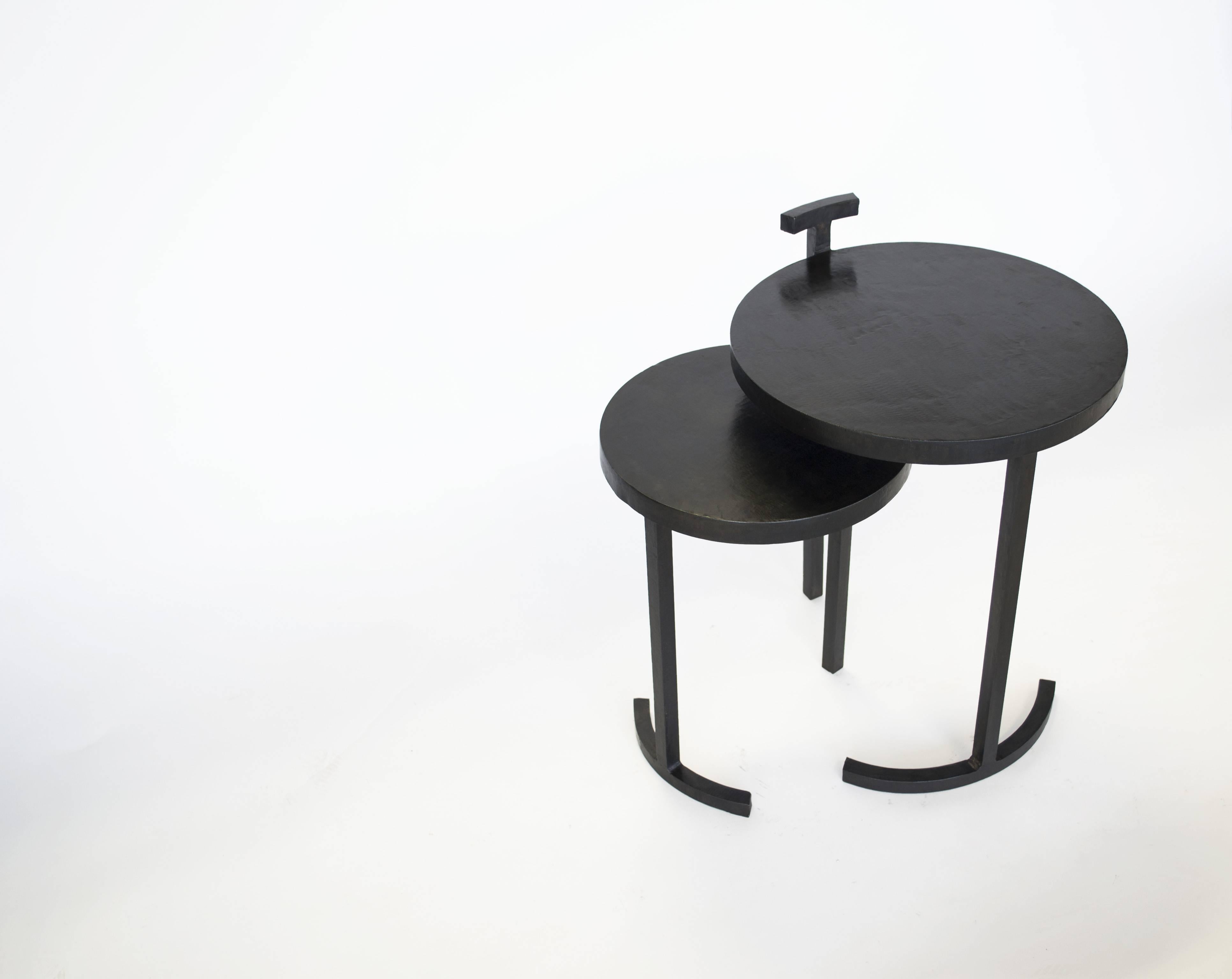 TABLE NO. 1 - NESTING PAIR 
J.M. Szymanski
d. 2017

Composed of two separate side tables—with each table only having two legs! This nesting side table is made from cast, blackened, and waxed steel. This uniquely designed frame allows for a 1-inch