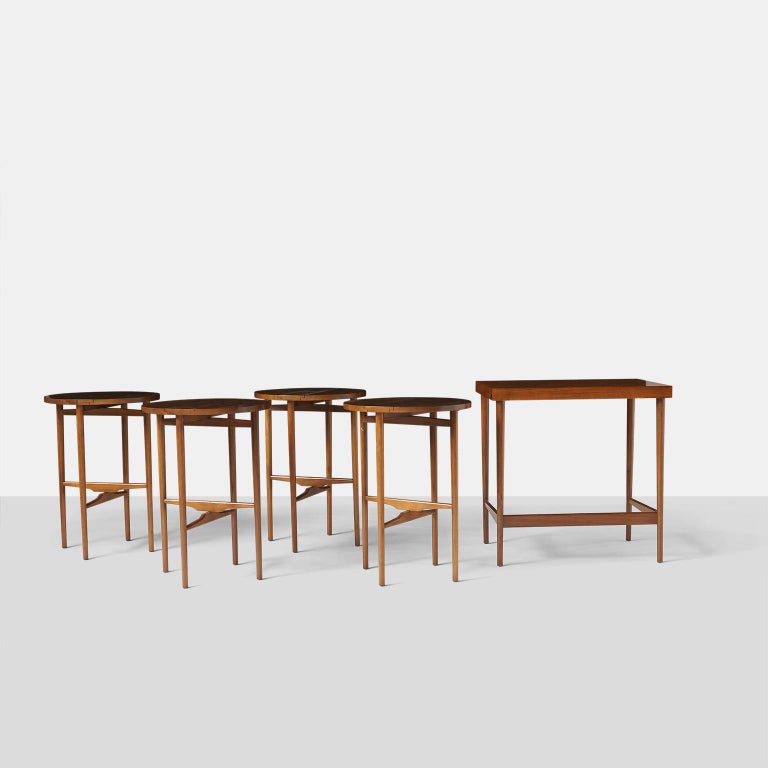A group of 4 round walnut nesting tables that fold and store underneath a rectangular version. The set was designed by Bertha Schaefer in the 1950’s and produced by Singer & Sons. Retains the original label. The rounds tables are 16.5? in diameter