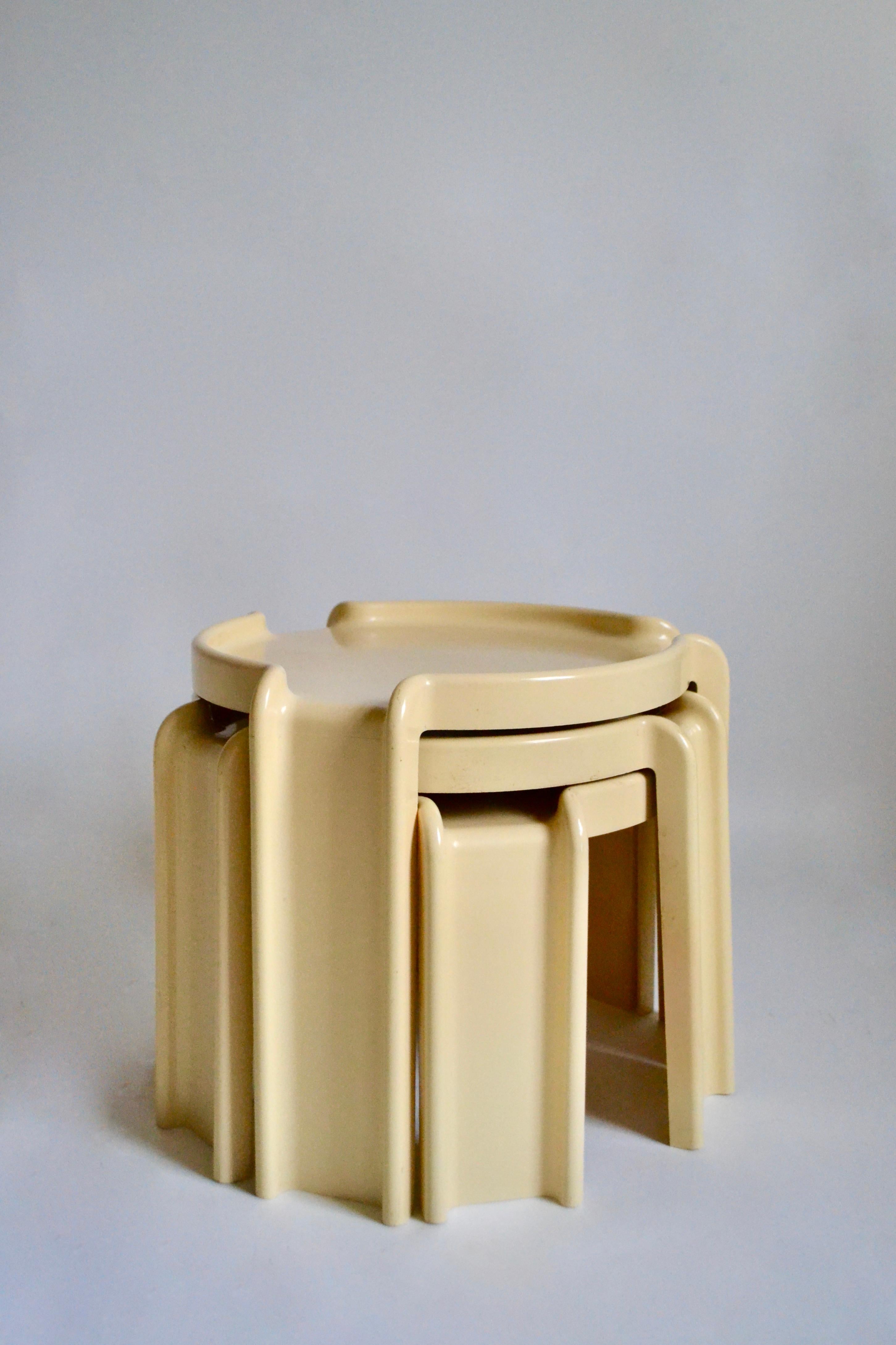 Trio of plastic cream nesting tables designed by Giotto Stoppino for Kartell in the 1970s. Designed in Italy and manufactured in Australia. Makers stamp at base of each table. Scuffs and wear commensurate with age, not distracting from the overall