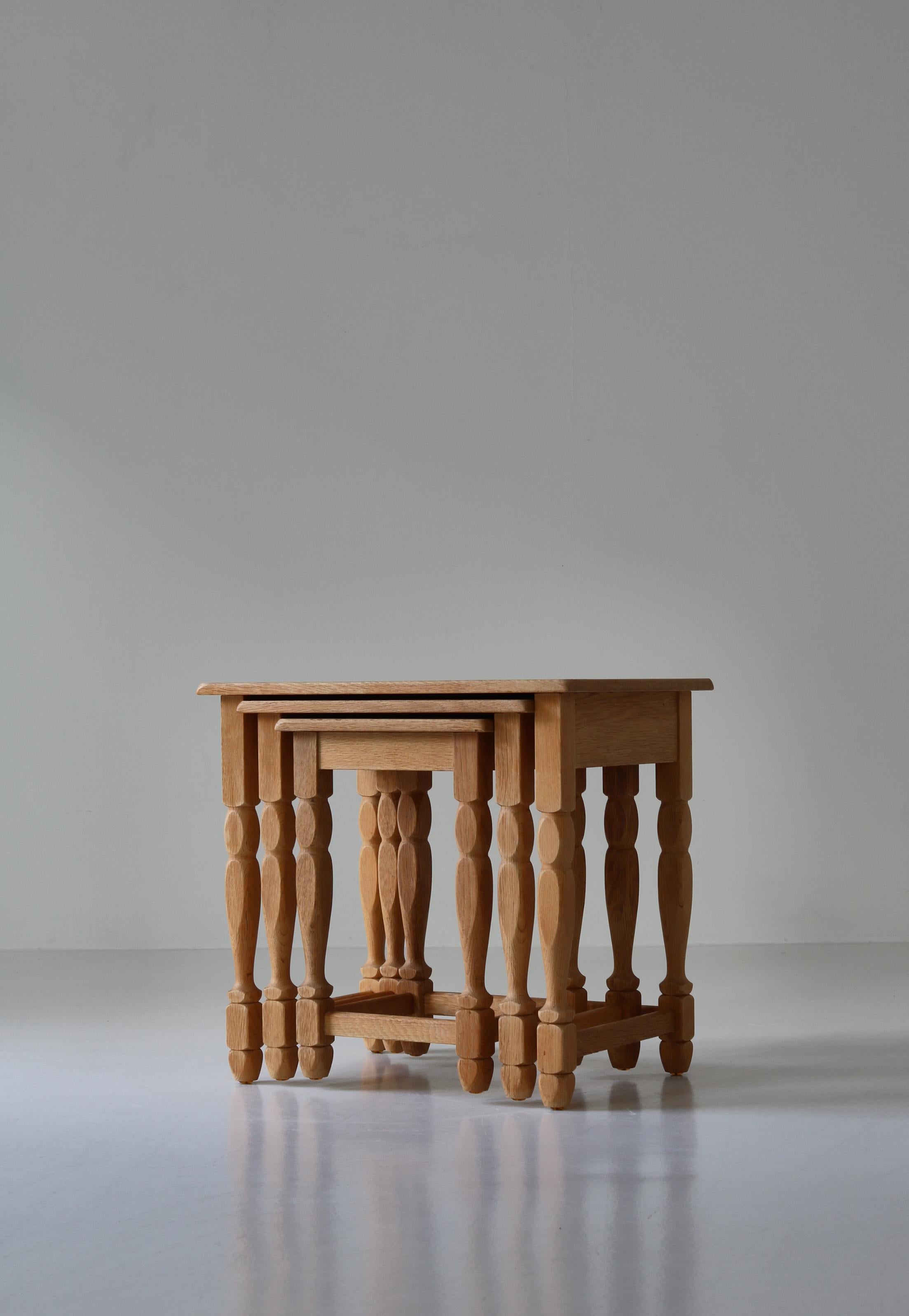 Set of 3 nesting tables in solid quartersawn oak with beautiful grain and patina. The tables were designed by Henning Kjærnulf in the 1960s and manufactured at EG Kvalitetsmøbel, Denmark. The style is modern but with playful hints to historical