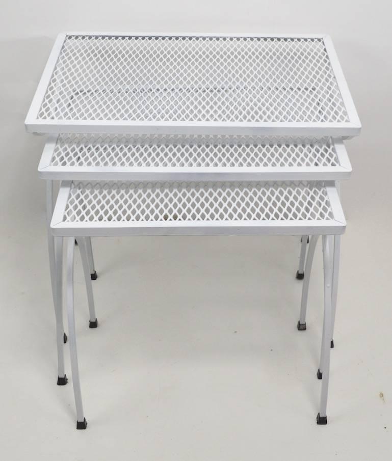 Set of three graduated tables with metal mesh tops and wrought iron legs by Salterini. These tables are in very good condition, they are recently repainted (white spray paint finish). Usable as is or we offer custom powder coating if you prefer a