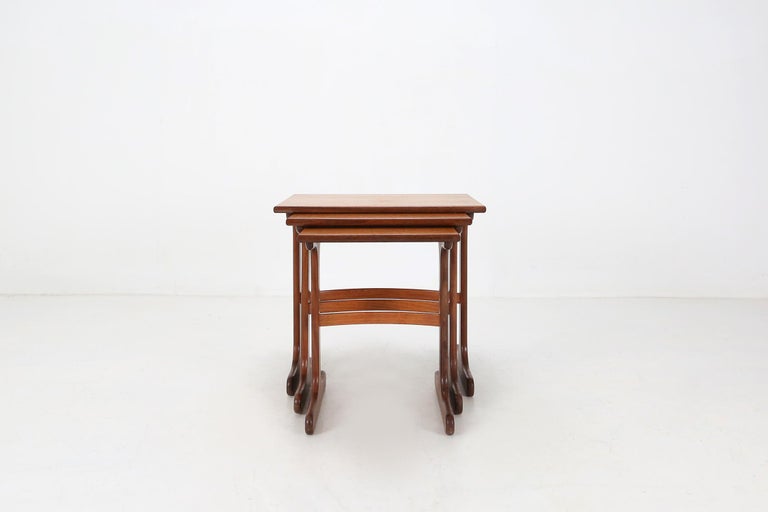 These nesting tables are made of teak veneer and sit on solid teak legs. This elegent set are easy to store as they fit under each other and are very useful.
Some small user damage on the table top.