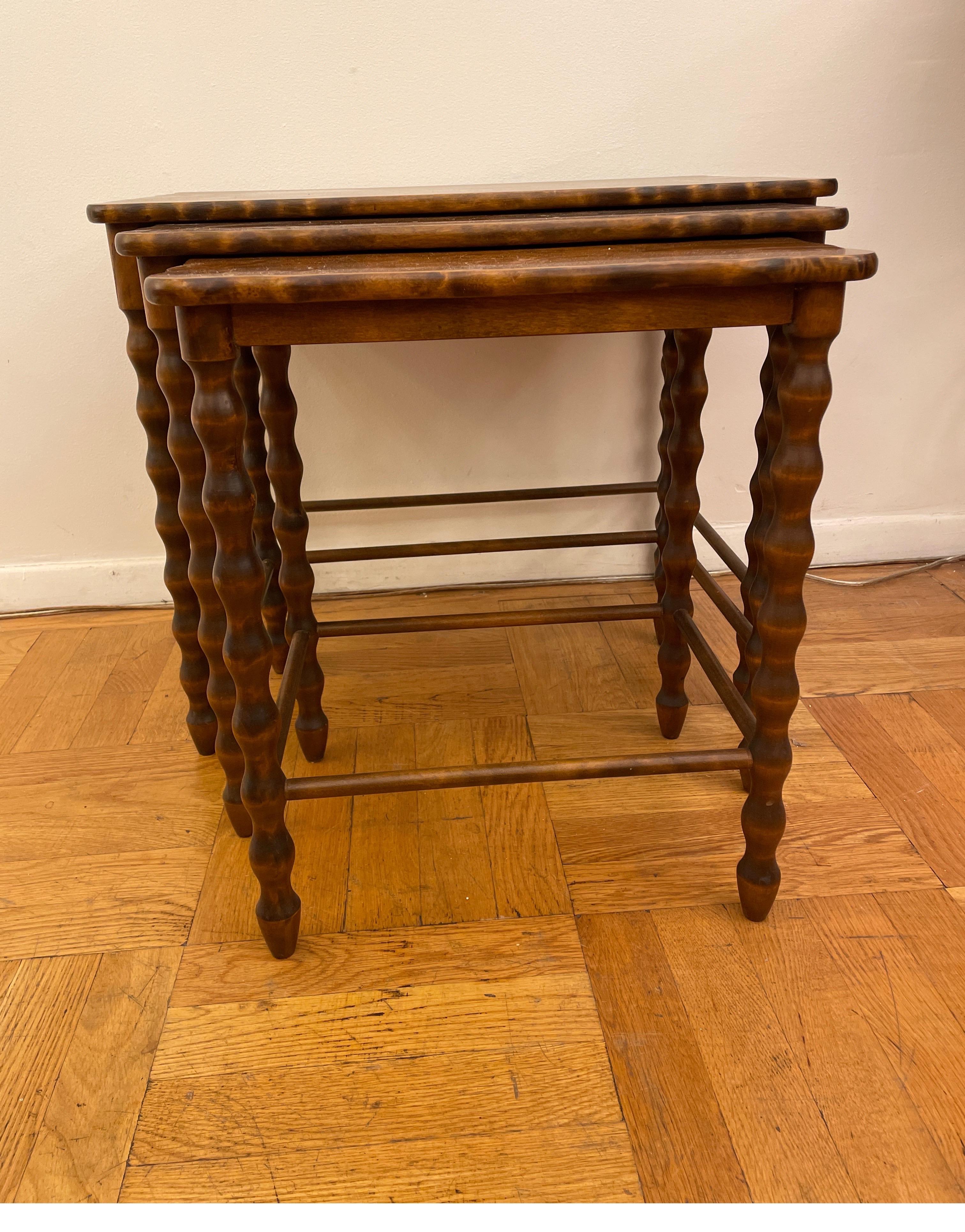 Lovely set of nesting tables crafted of solid walnut stained birch, with the highly sought after barley twist legs and bevelled edges. The two lower tables slide into grooves in the apron and 