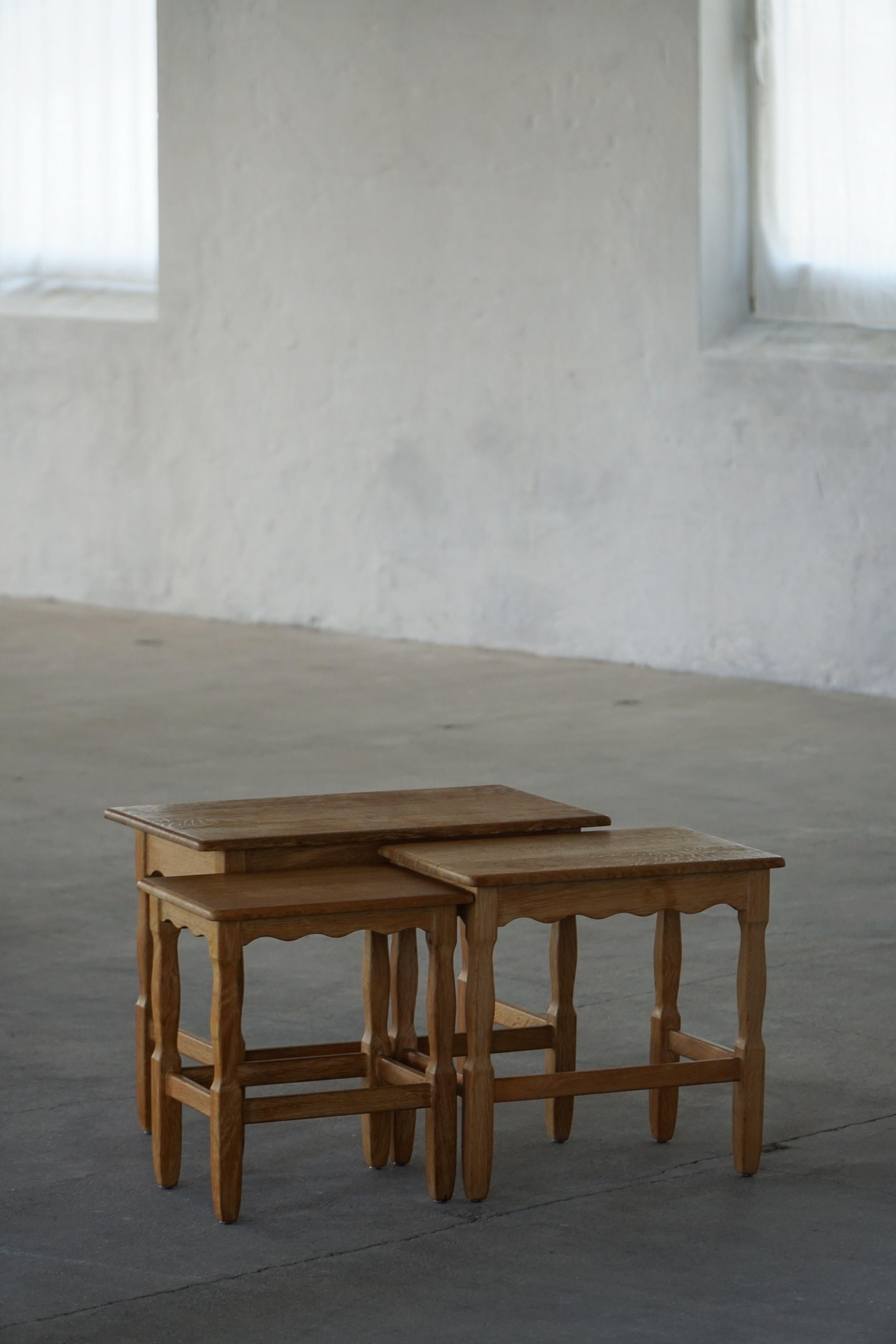 A refined and decorative set of three oak nesting tables, crafted in the 1960s in the style of Danish designer Henning (Henry) Kjærnulf. These tables display the hallmarks of Danish design from the period, with elegantly carved and detailed legs