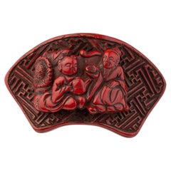 Nestuke in red lacquer carved in theform of a fan using the tsuishu technique