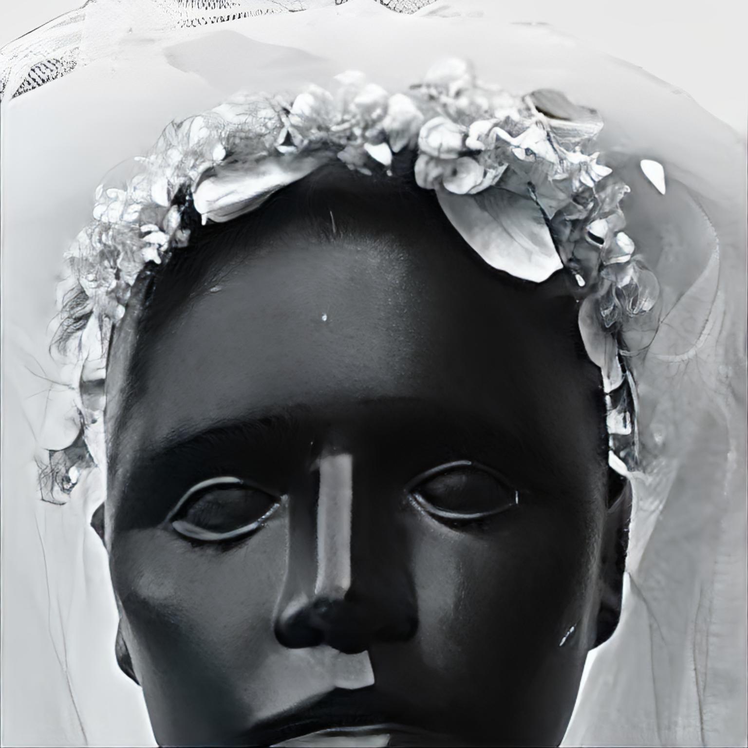 Net wedding veil with a silk head piece, dating from the 1960s. There are four layers of net, measuring length approximately 24 inches. The head piece is made from silk leaves and flowers, the flowers have faux pearl centres. The leaves and flowers