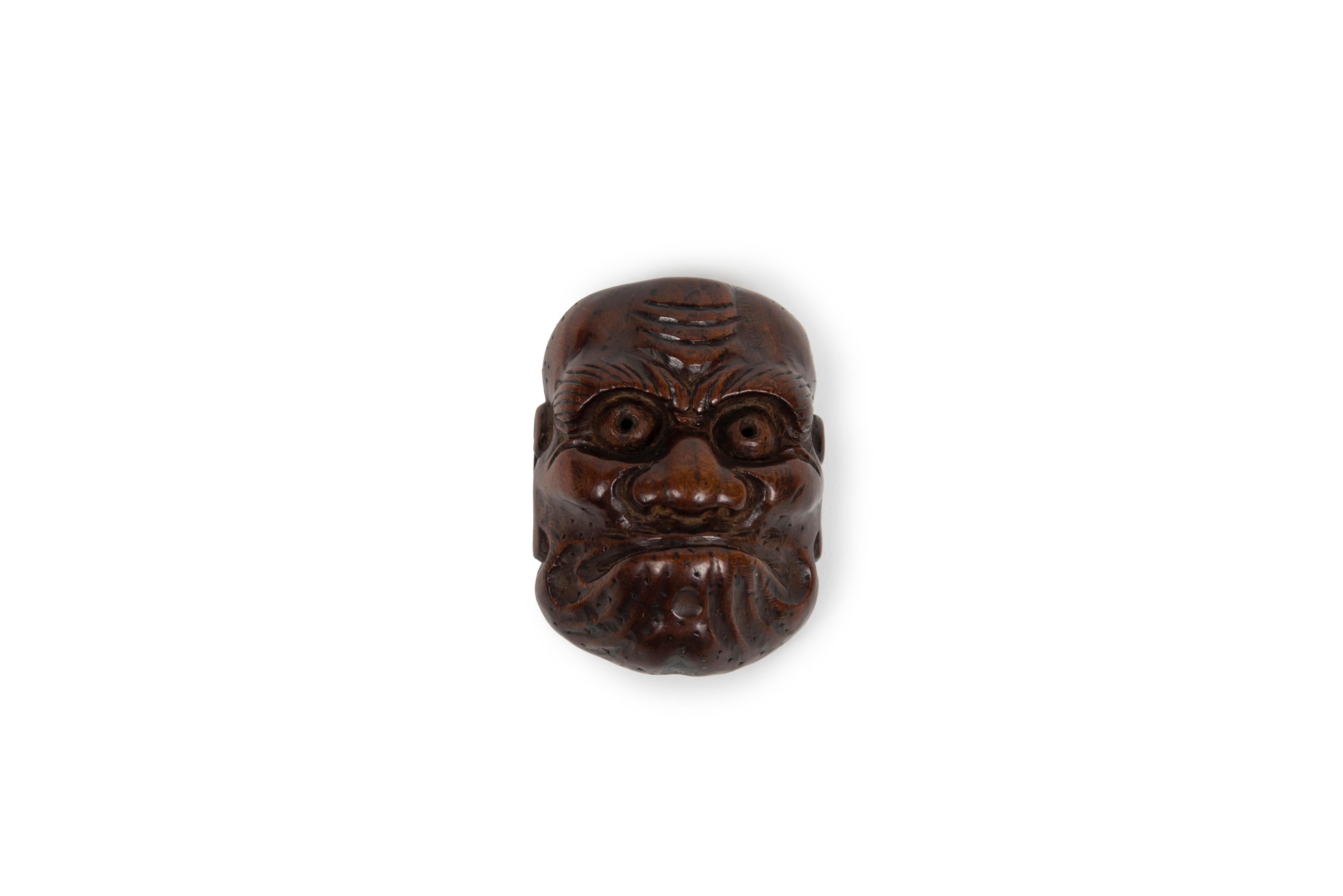 Boxwood netsuke representing the mask of Hyottoko in Noh theatre.
Hyottoko is a legendary comic character, considered to be a fire god in certain regions of north-east Japan. The shape of his grimacing mouth is explained by the fact that he blows