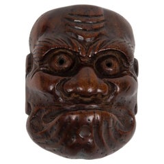 Netsuke en forma de máscara No que representa al personaje de Obeshimi