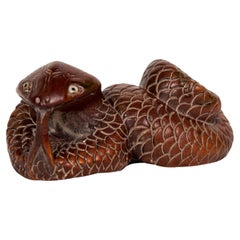 Netsuke en forma de serpiente en madera de boj con ojos incrustados y firma