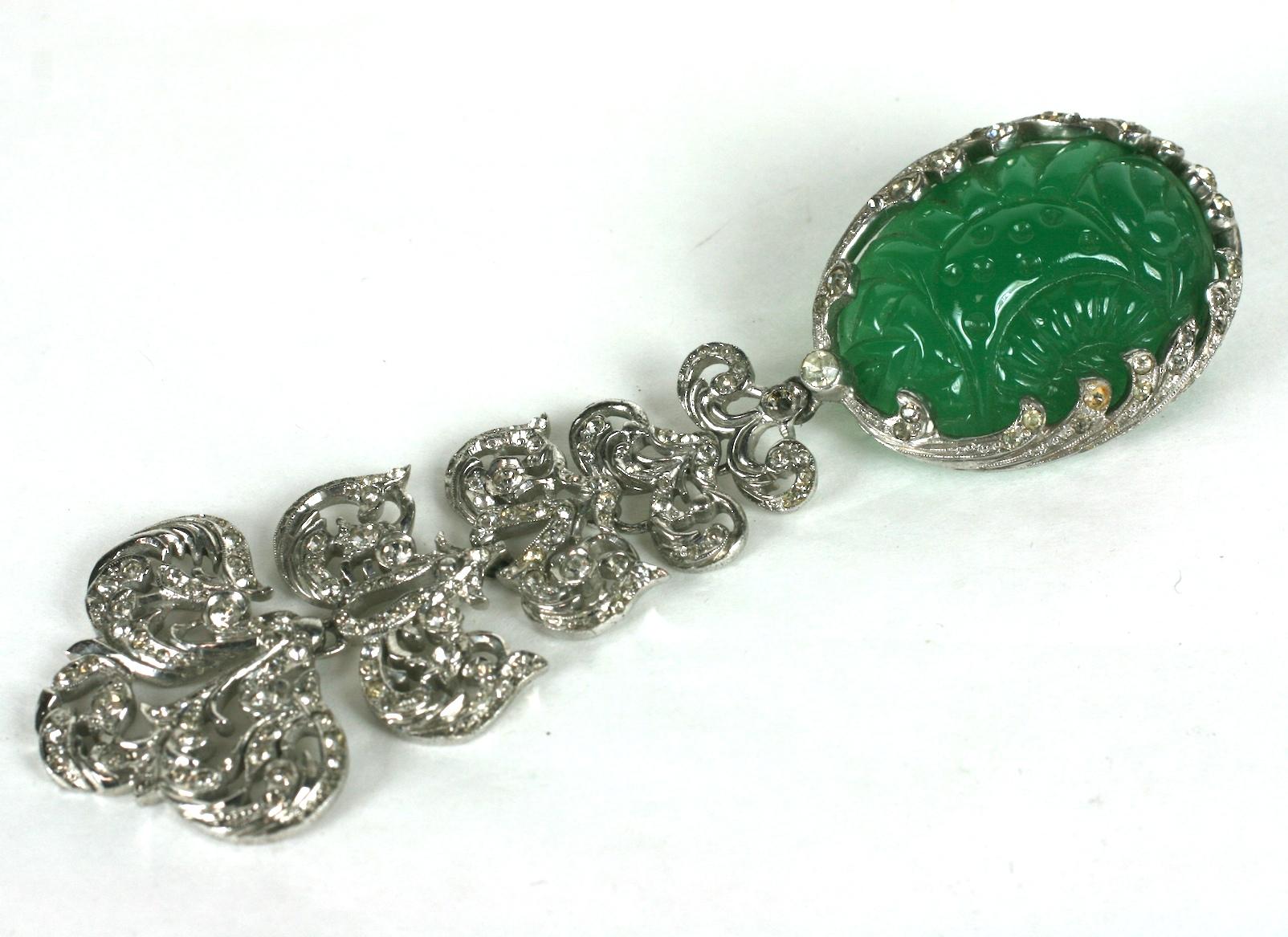 Nettie Rosenstein Art Deco articulated pendant clip brooch of rhodium plated sterling silver set with crystal rhinestone pave. The brooch top with a large oval faux jade cabochon which is carved and incised, set into a sterling silver and pave