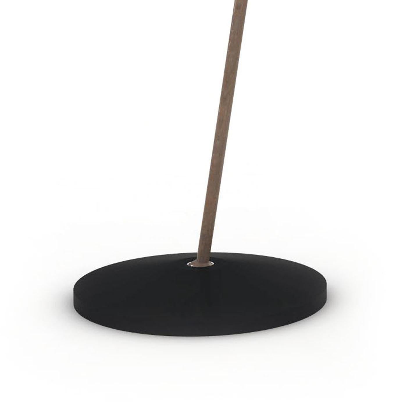 A modern interpretation of the iconic gooseneck lamp, this desk lamp features a round base and shade in metal with a glossy black finish. The shaft, curved to accomodate the large opening of the shade, is in brass with an elegant bronze finish that