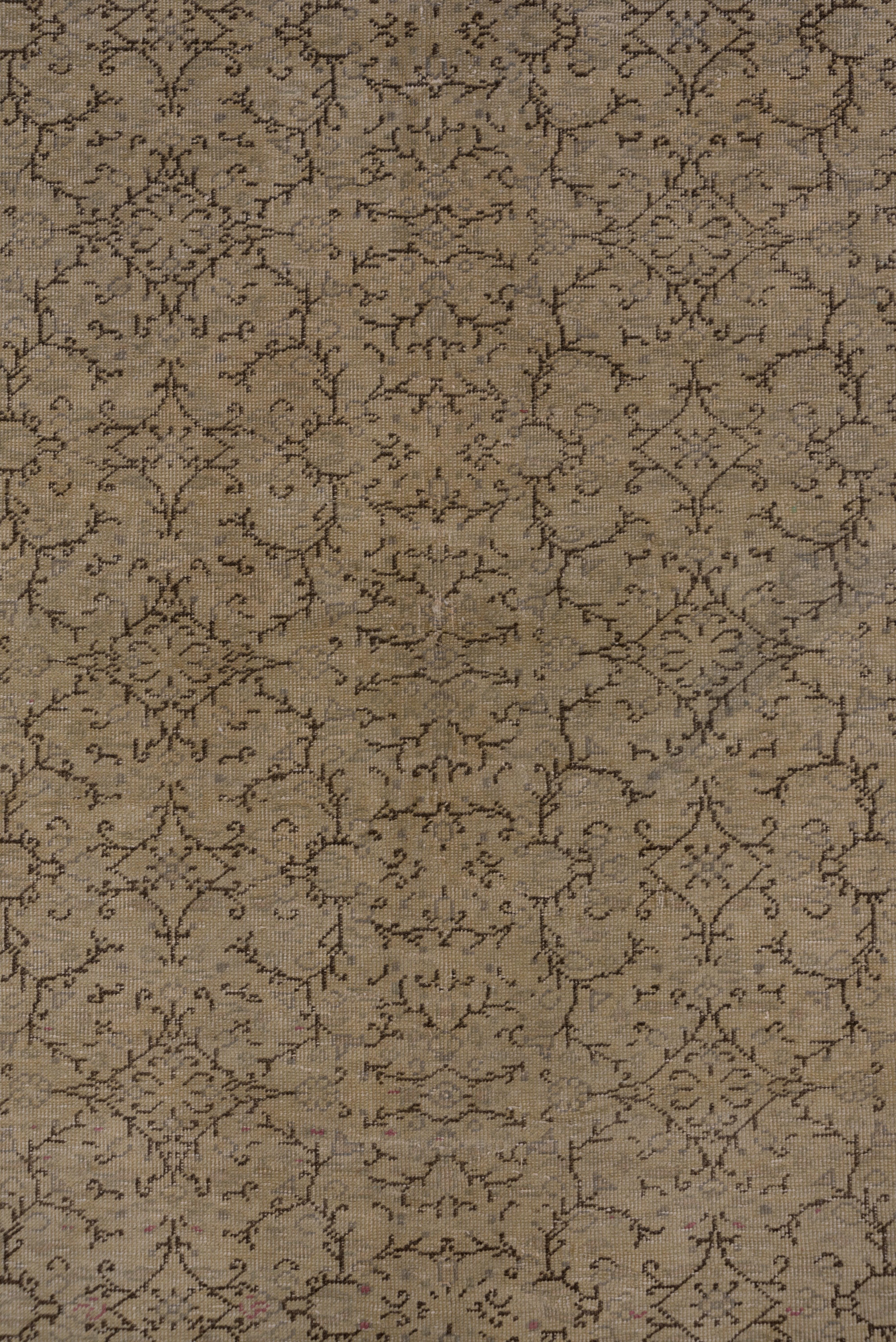 This eastern Anatolian town carpet has a straw ground uniformly decorated with slender open diamonds, and broken and branching short stems in dark brown, and very pale green small flowers. The straw border has ornaments in dark brown, ecru and pale