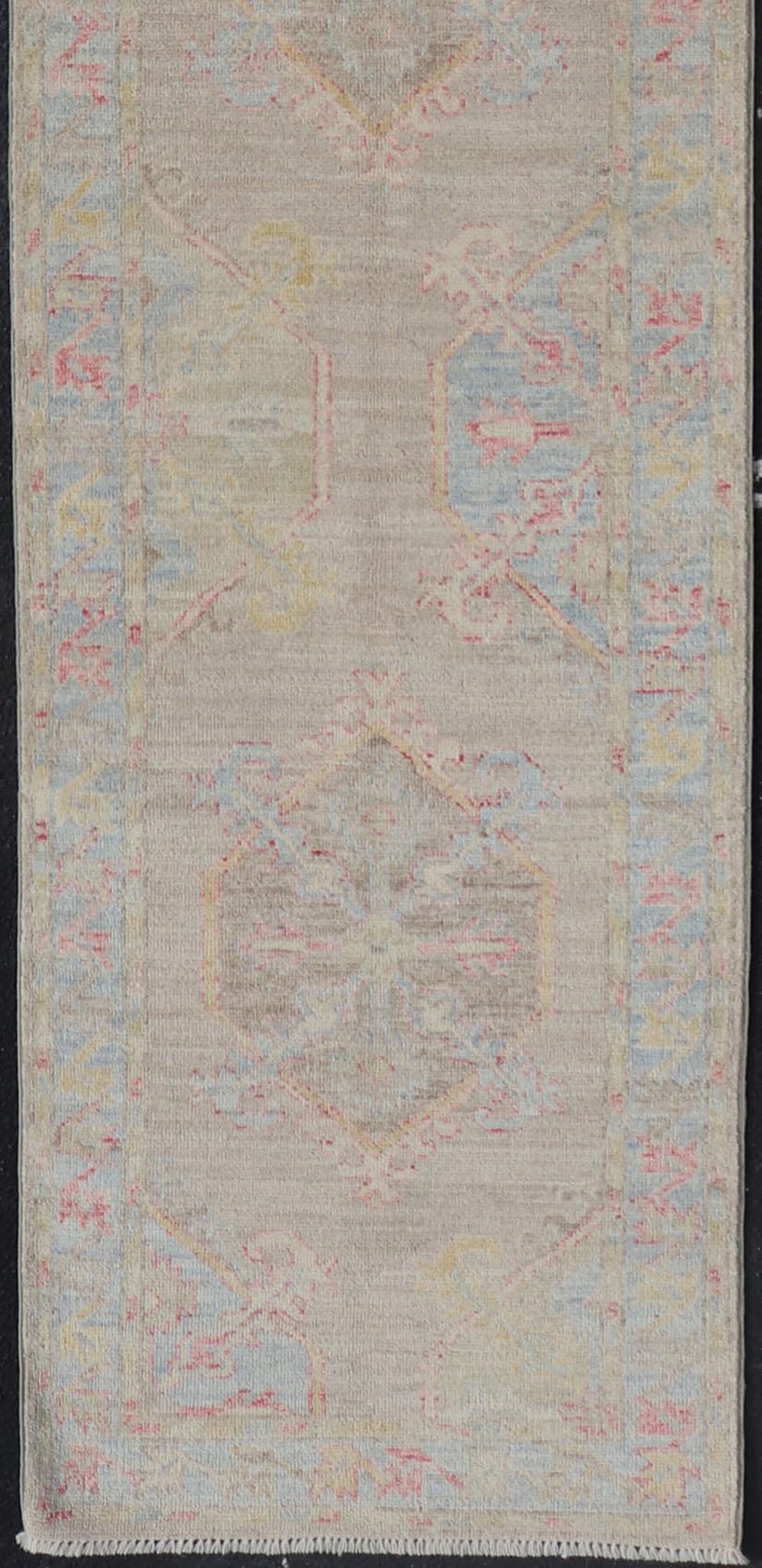Hand-Knotted Oushak runner with Medallion Design on a Tan Field With Red & Blue. Keivan Woven Arts; rug AWR-AR118 Country of Origin: Afghanistan Type: Oushak Design: Medallion, Motif, Floral Motif

This modern piece holds large medallions in the