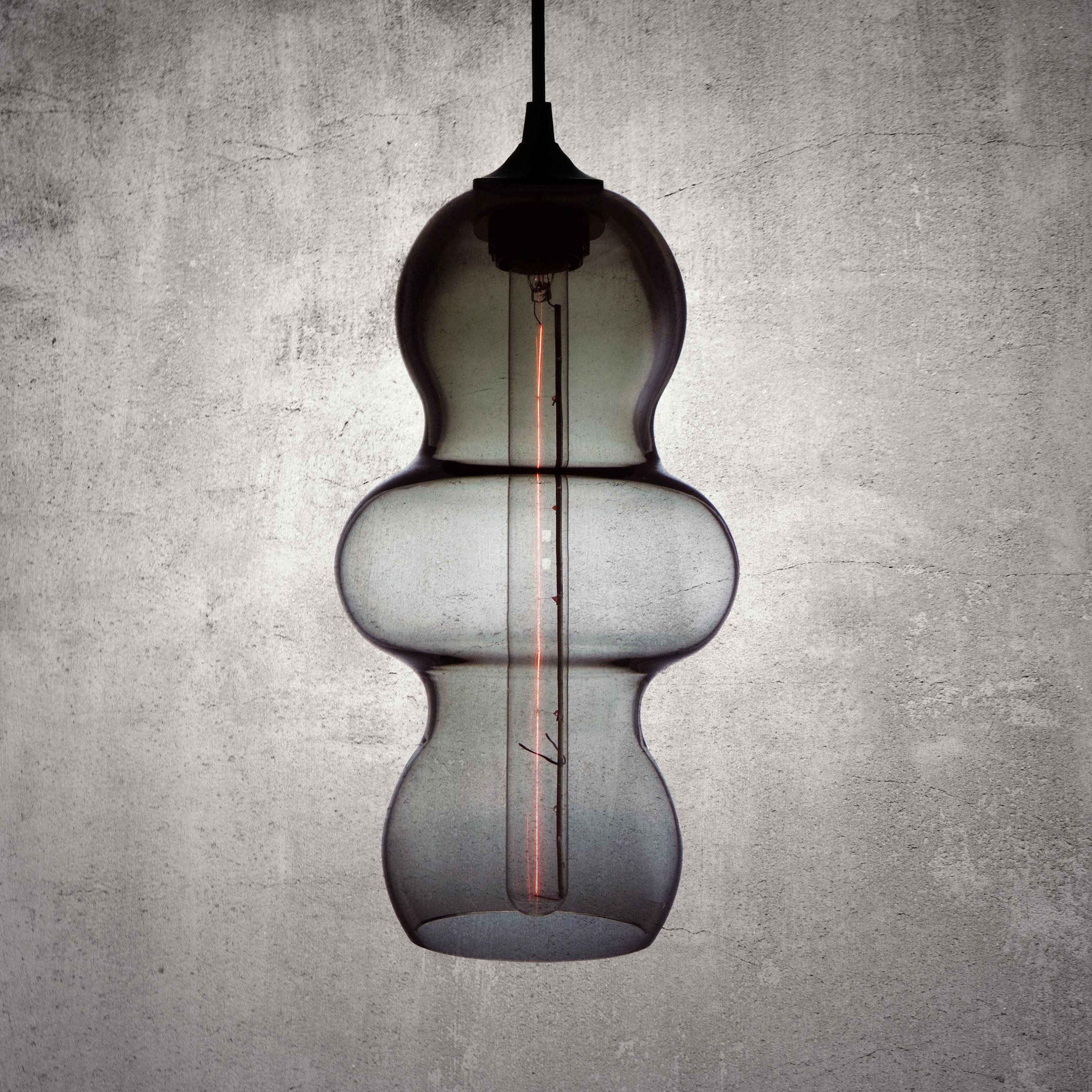 The Tamarindo contemporary glass pendant lamp is a contemporary interpretation of the tamarind fruit. Encapsulating its characteristics, the Tamarindo is sleek, curvaceous and light, hanging effortlessly with its long elongated form juxtaposed by a