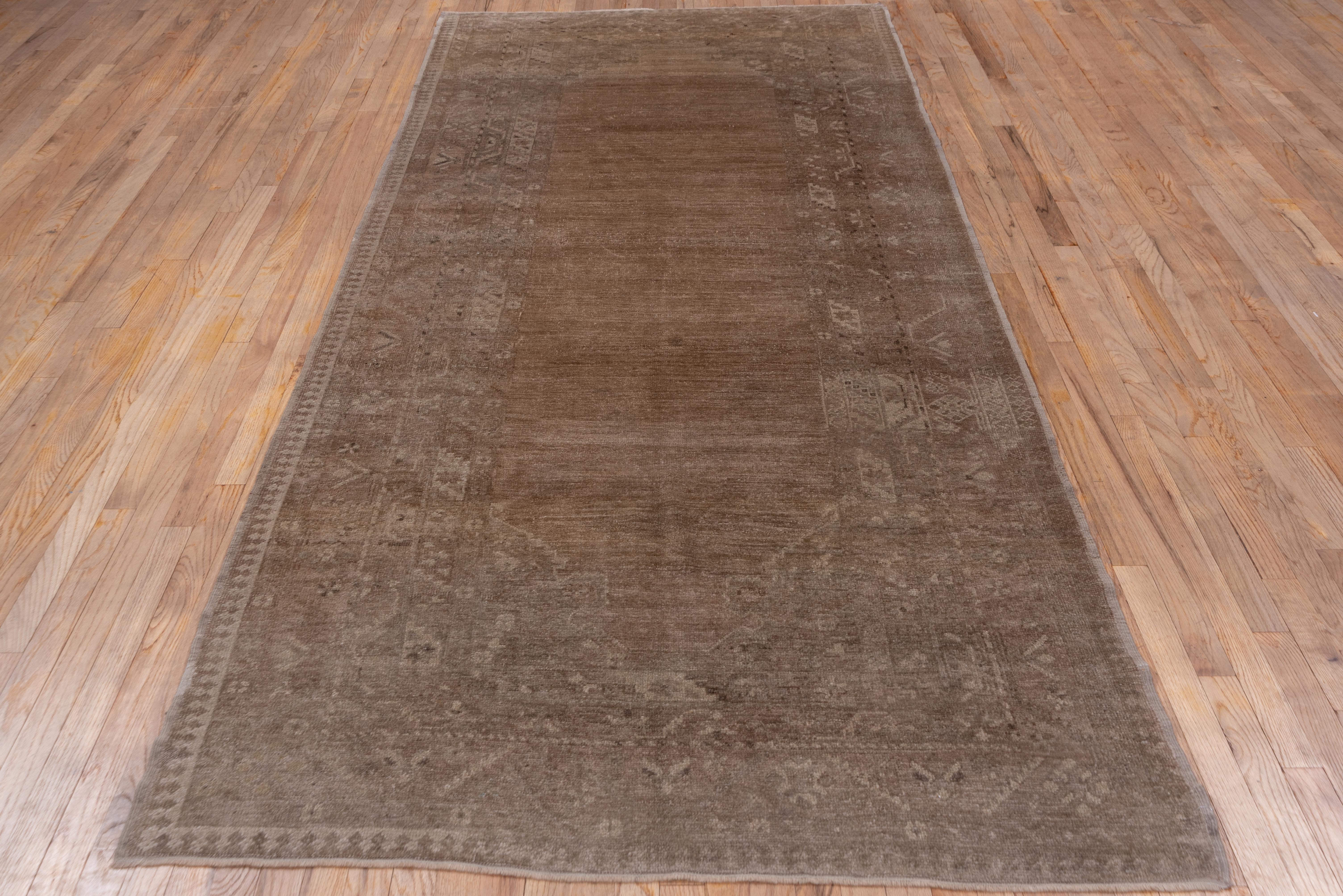 In tones of putty, beige, light brown and tan, this good condition western Turkish town rug shows a well abrashed field set within rosette and palmette corners and framed by a set of six patterned borders including keyhole reciprocal, rosette and