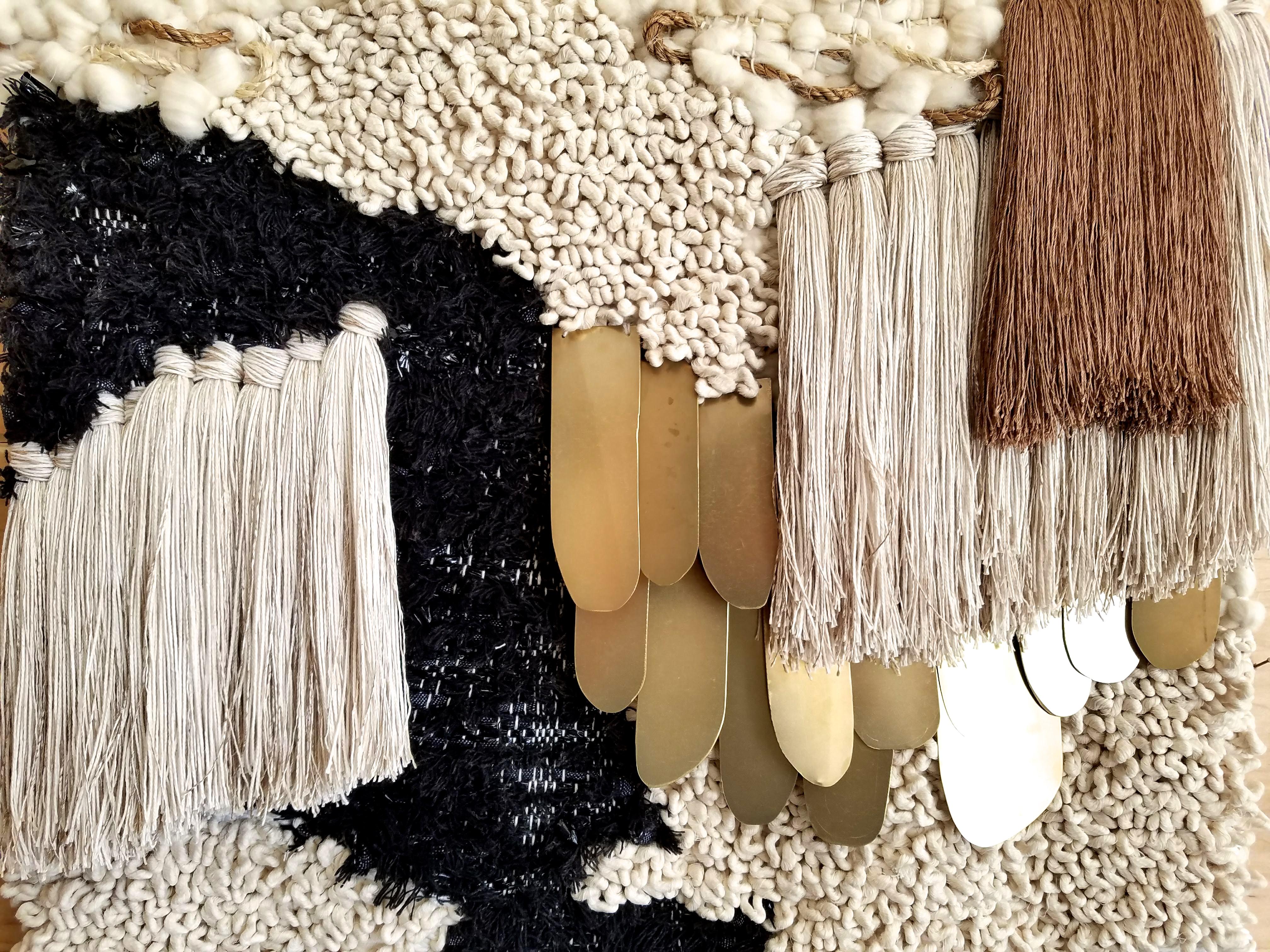 Handwoven, tapestry style, woven wall hanging by Janelle Pietrzak of All Roads. Neutral colors, shiny beige yarns, hand cut brass shapes and various types of ropes and natural fibers are used in this textile. Weaving hangs from a steel rod.

This