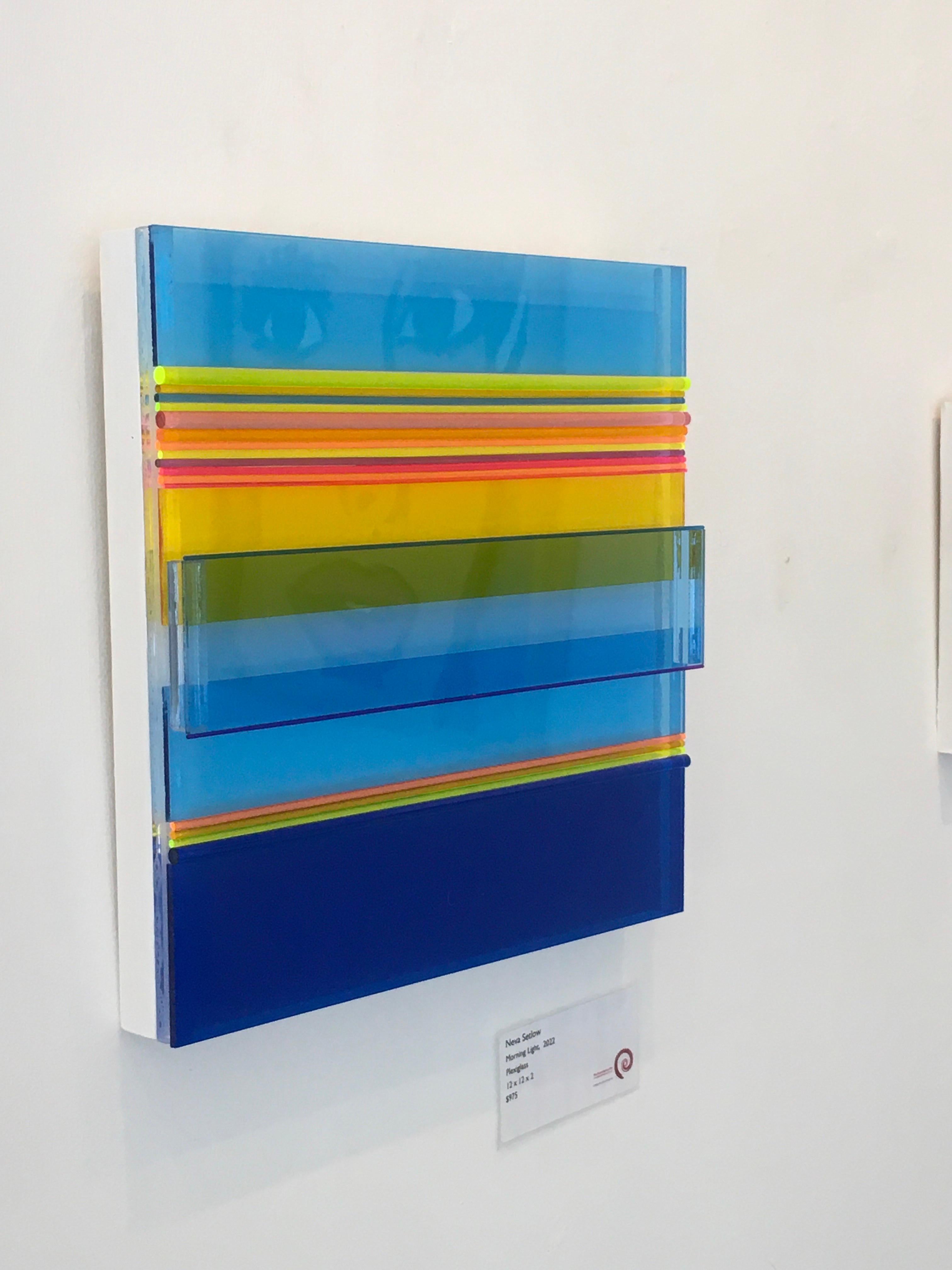 Morning Light by Neva Setlow is created with layered colored Plexiglass, both flat and round.  It is 12x12x2 created with bright colors and dimension.   It is filled with blues and yellows.  It is on a wood frame and wired for easy hanging.   It is