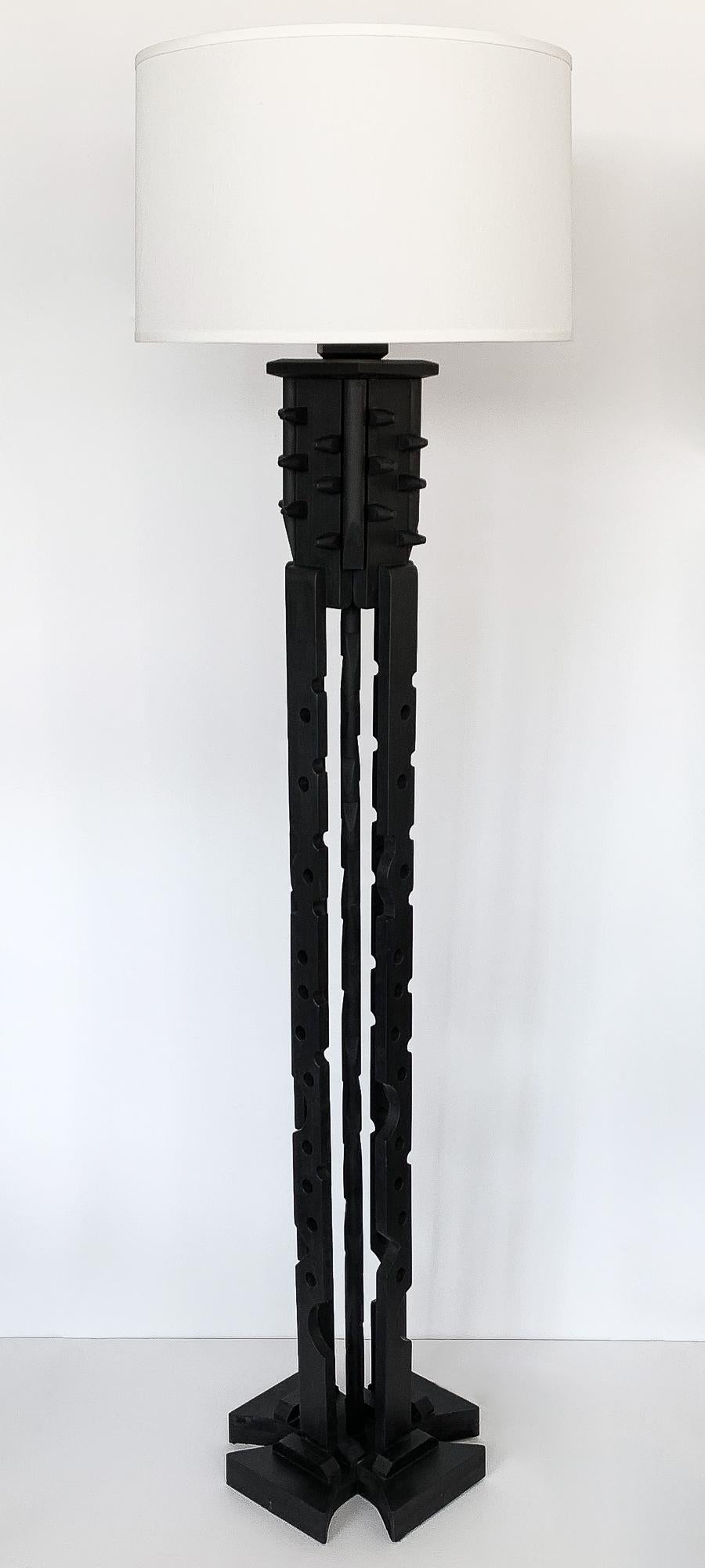 Unique black painted wood assemblage floor lamp inspired by Louise Nevelson. Four abstract geometric supports with cutout create the open framework of this sculptural lamp. Cross shaped base. Wooden spike detail along top portion of the lamp on all