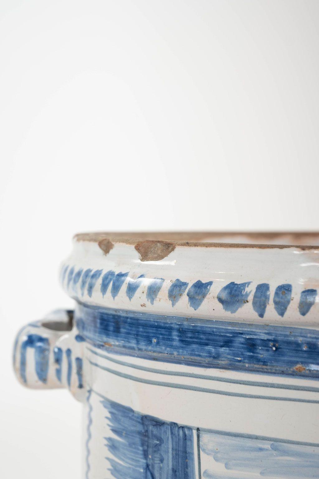 Olla de Naranja de loza de Nevers adornada con escenas de granja pintadas y decoración de roleos en tonos azules (camaieu bleu). Este macetero de estaño vidriado de hacia 1780-1800 procede de Nevers (Francia), importante centro de producción de loza
