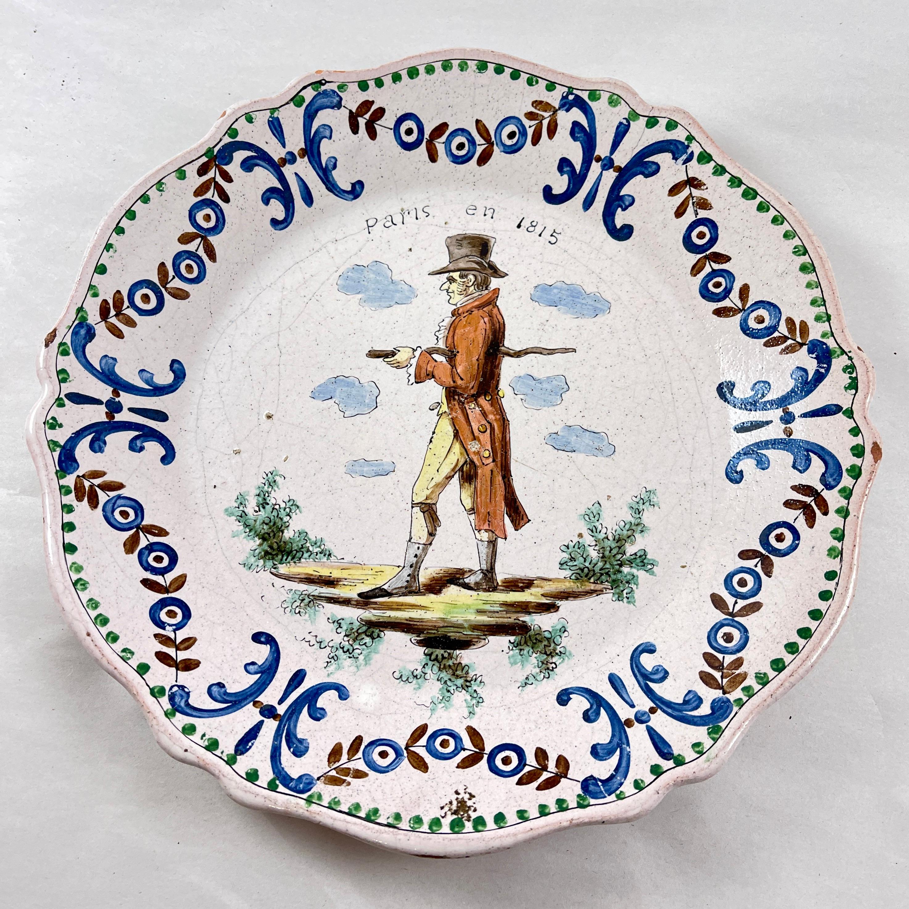 A French Faïence plate showing the men’s fashion in Paris during the early 19th Century, likely made in Nevers, France –  circa 1900.

The scallop rimmed plate is fashioned in the style of 18th Century faïence, using the molds, glazing, and firing