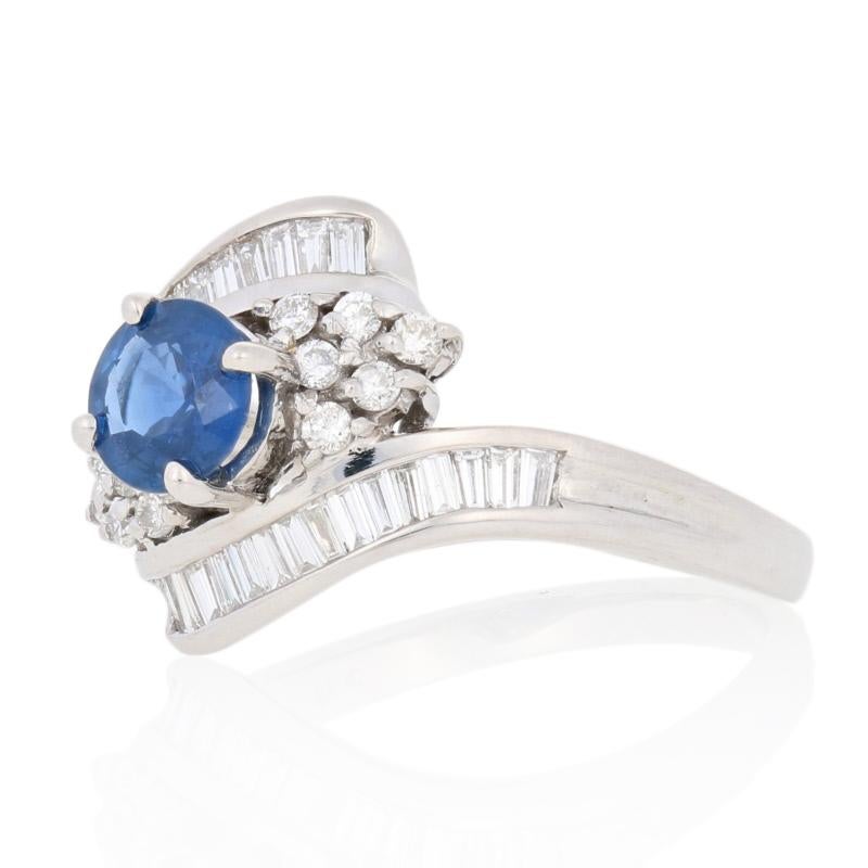 Add a sparkling touch of color to your evening attire with this gorgeous NEW ring! Featuring a graceful bypass design, this 18k white gold piece showcases a satin blue sapphire framed by shimmering diamonds. 

This ring is a size 7 1/4, but it can