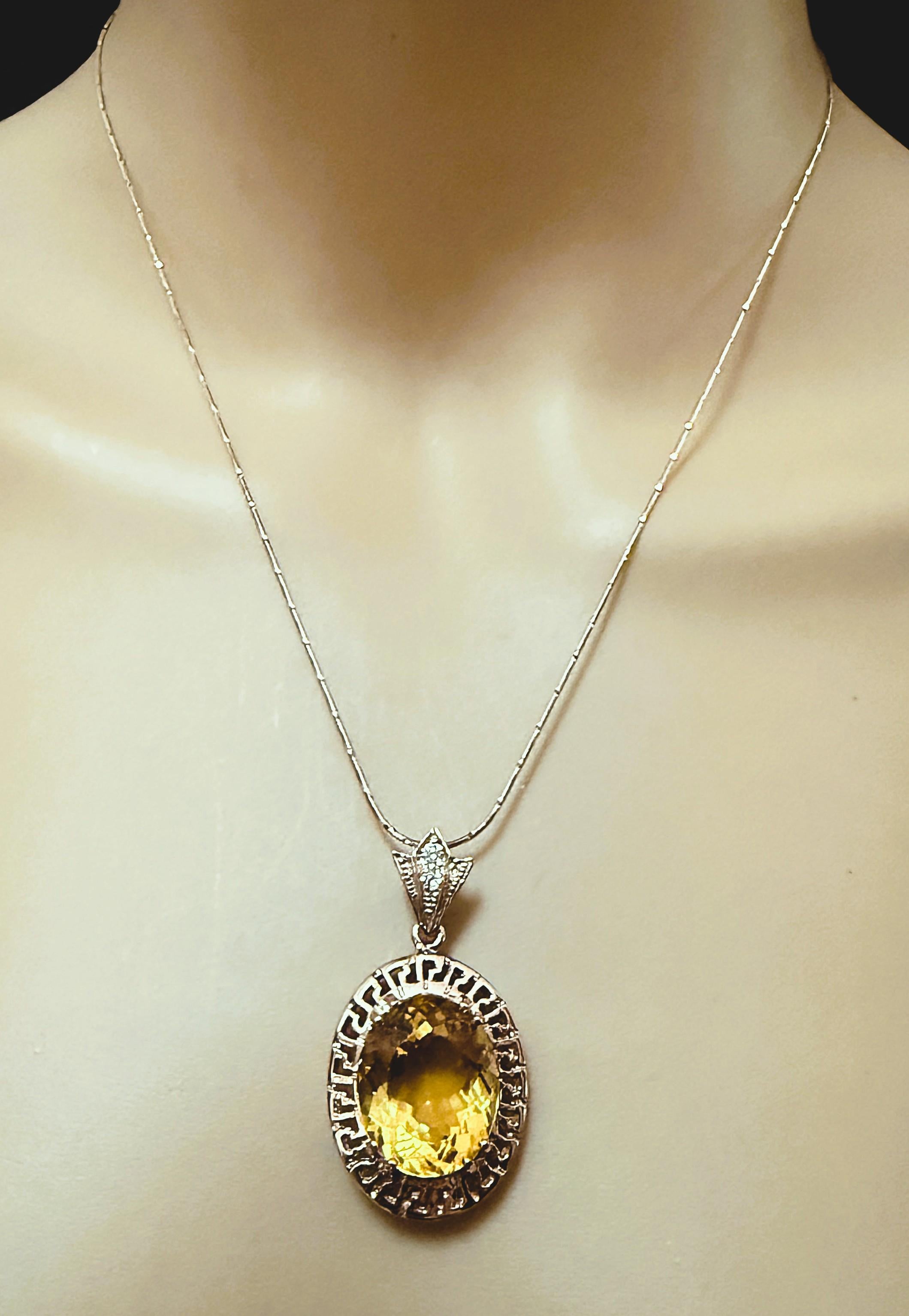 ¡Qué colgante tan magnífico!  La piedra central es un citrino talla oval de fantasía y mide 14.80 quilates.  Mide 18 x 15,2 mm y está engastada en una preciosa corona de llave griega de plata de ley chapada en oro rosa.  En la presilla hay 2 zafiros