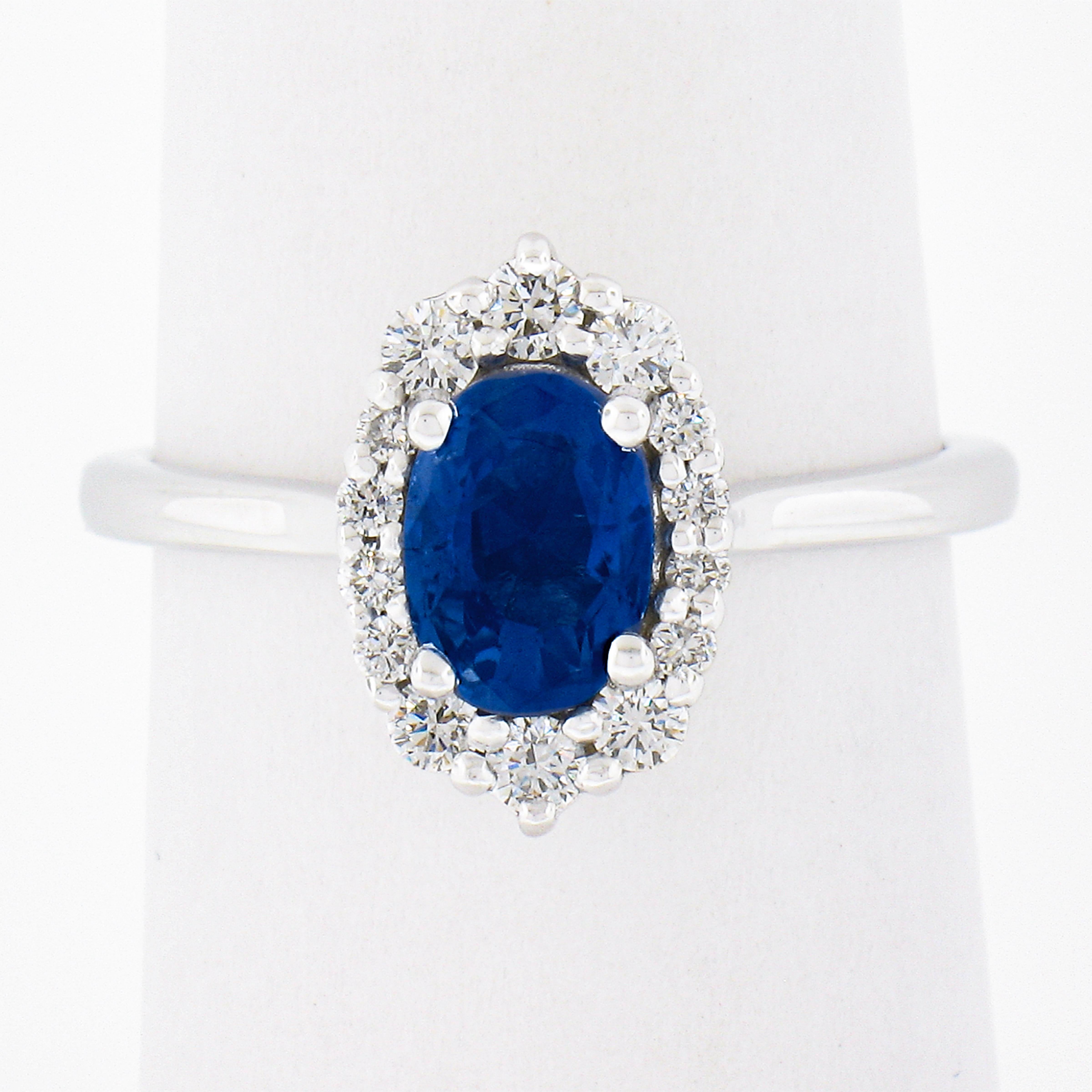 This truly breathtaking engagement or cocktail ring is newly crafted in solid 14k white gold and features a fine quality, GIA certified sapphire stone at its center. This 1.28 carat sapphire is then surrounded by a uniquely designed halo that is
