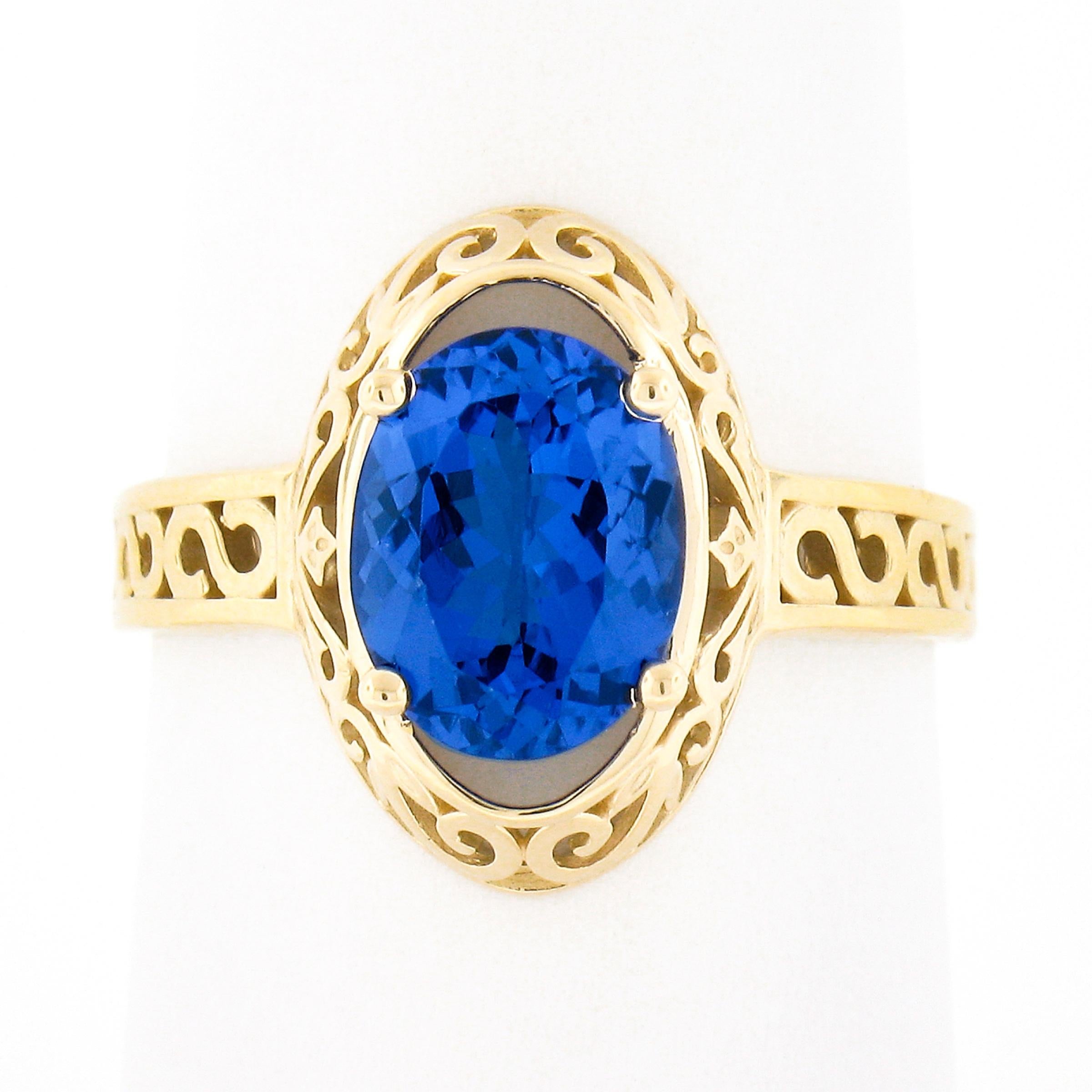 This gorgeous tanzanite ring is newly crafted in solid 14k yellow gold and features a beautiful, approximately 2.0 carat, tanzanite solitaire neatly prong set at the center of the elegant scroll open work design. The solitaire has an oval cut with