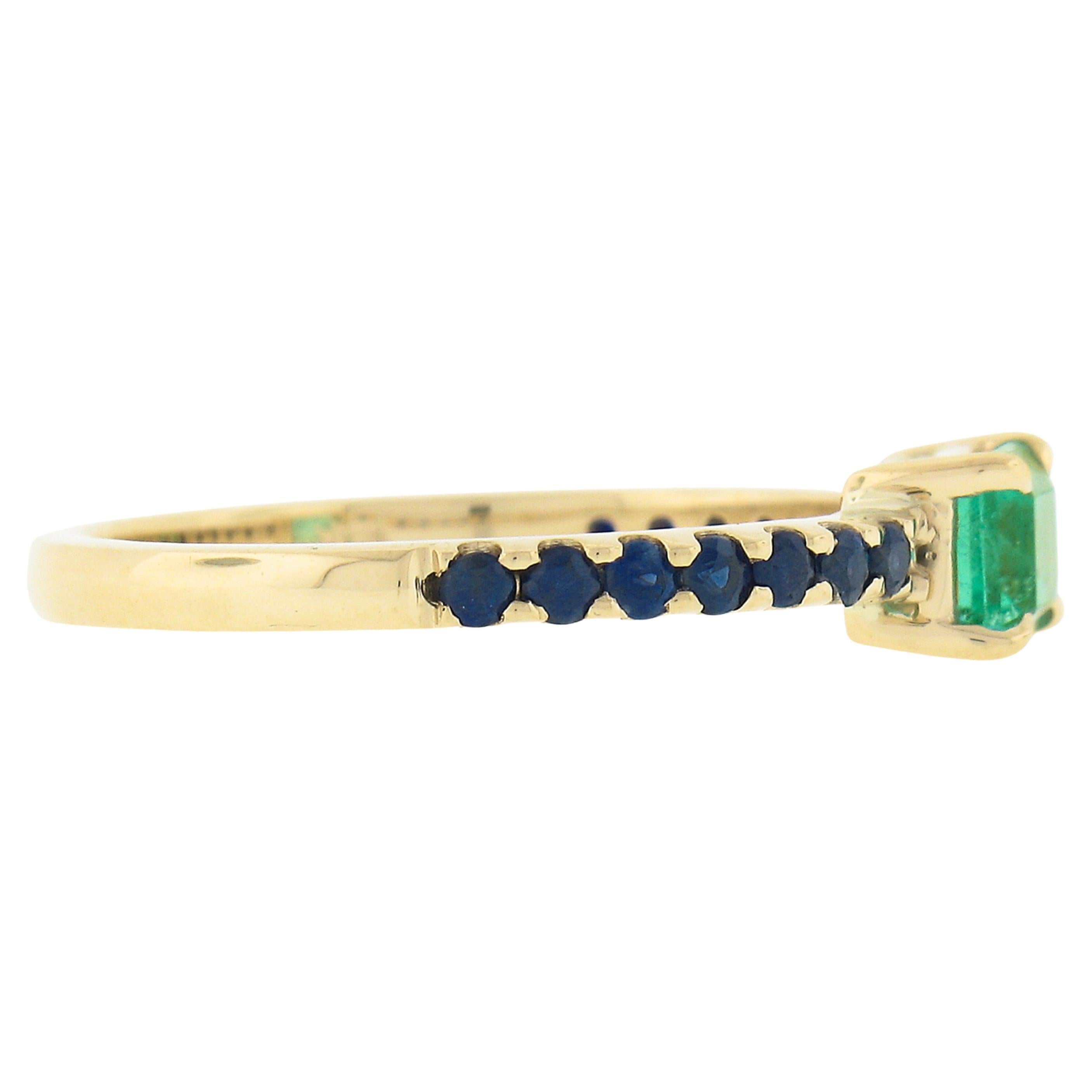 A simple yet gorgeous, Colombian emerald solitaire ring that is newly crafted from solid 14k yellow gold. The solitaire is emerald cut with a medium vibrant green color accented with 15 royal blue sapphires that are all set in prongs settings. This