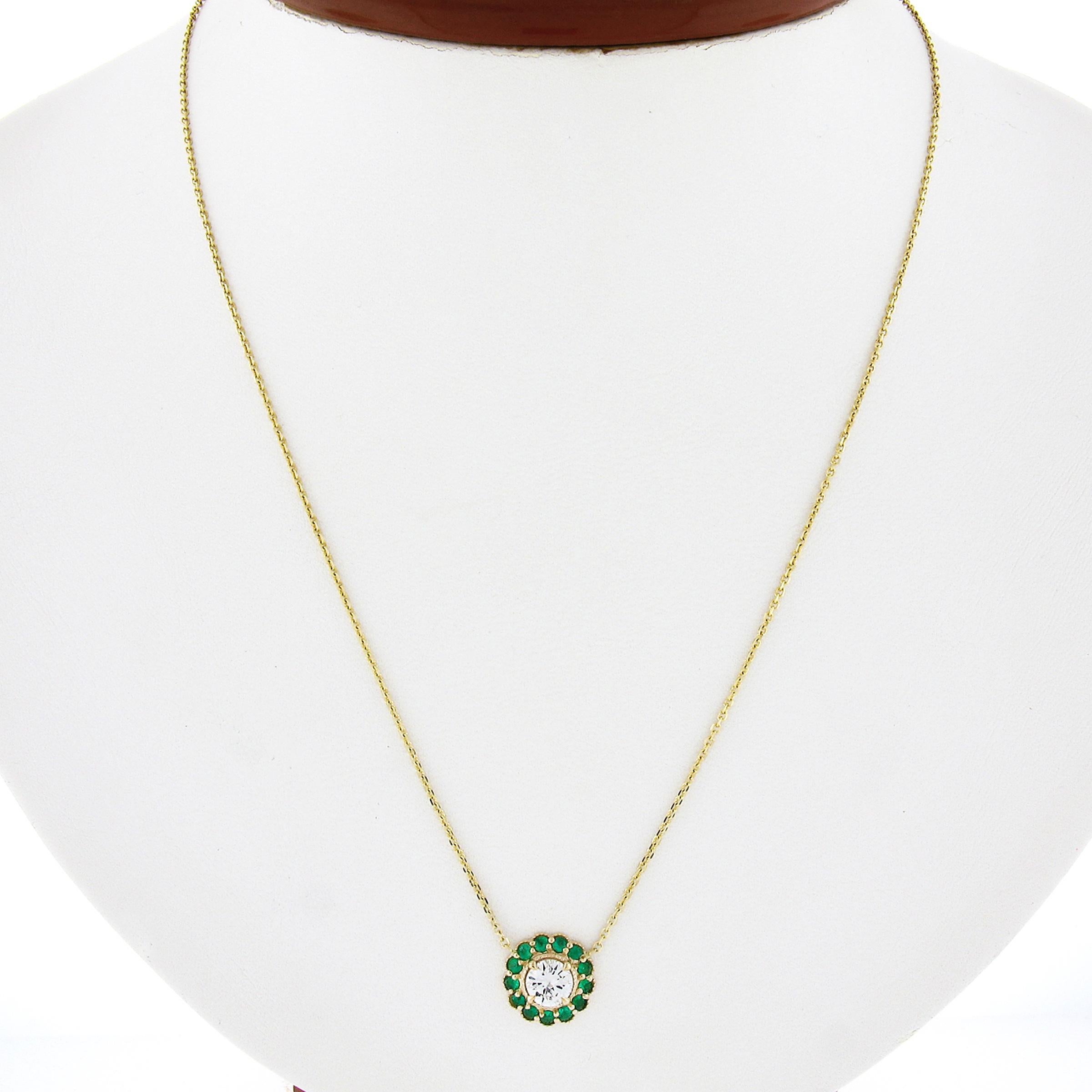 This gorgeous and very well made pendant necklace is newly crafted in solid 14k yellow gold and features a stunning diamond neatly prong set at the center of a vibrant emerald halo. The round brilliant cut diamond is an attractive size at 0.52