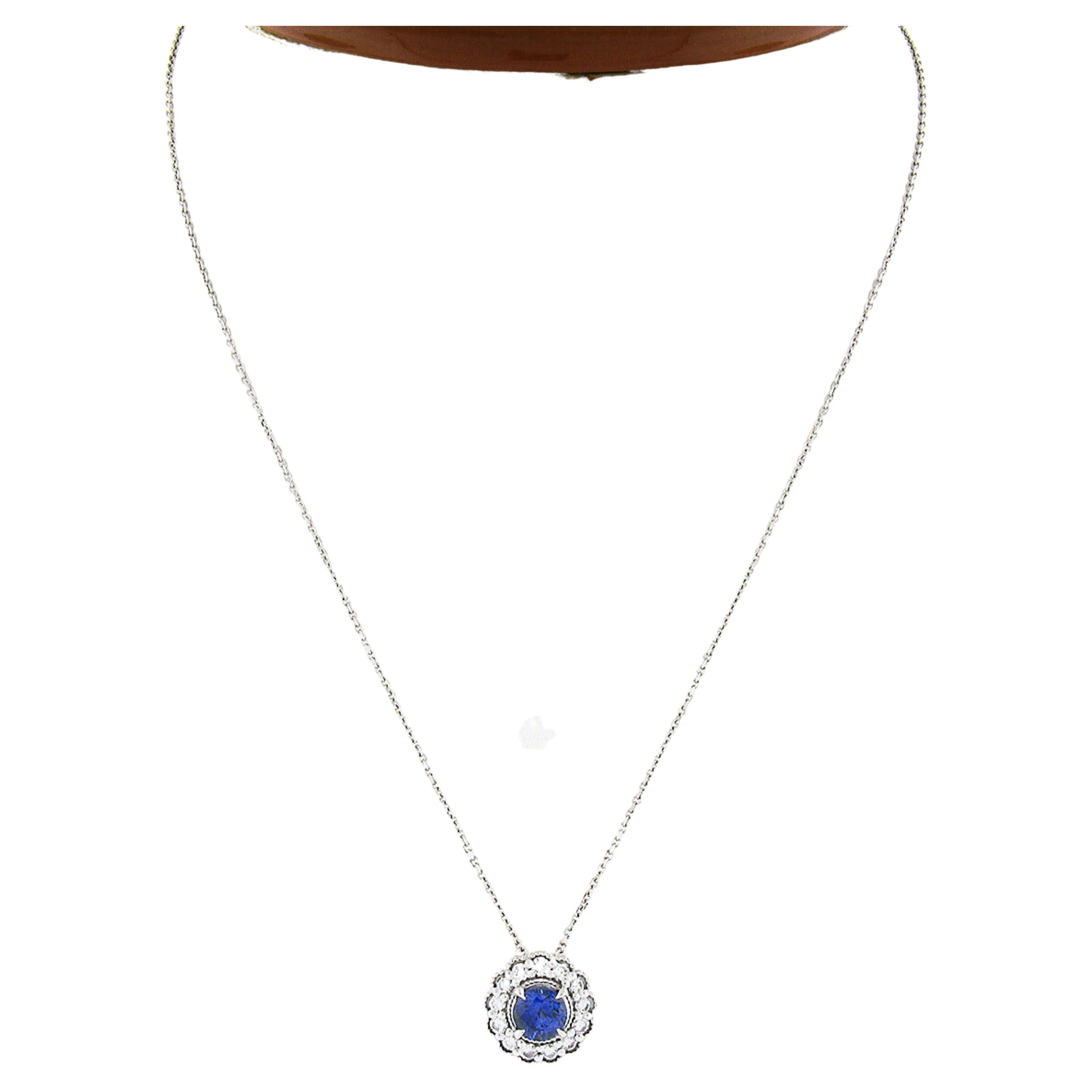 This stunning pendant necklace is newly crafted in solid 14k white gold and features a gorgeous sapphire neatly prong set at the center of a fiery diamond halo. The round brilliant cut sapphire is an attractive size, weighing exactly 1.03 carats,