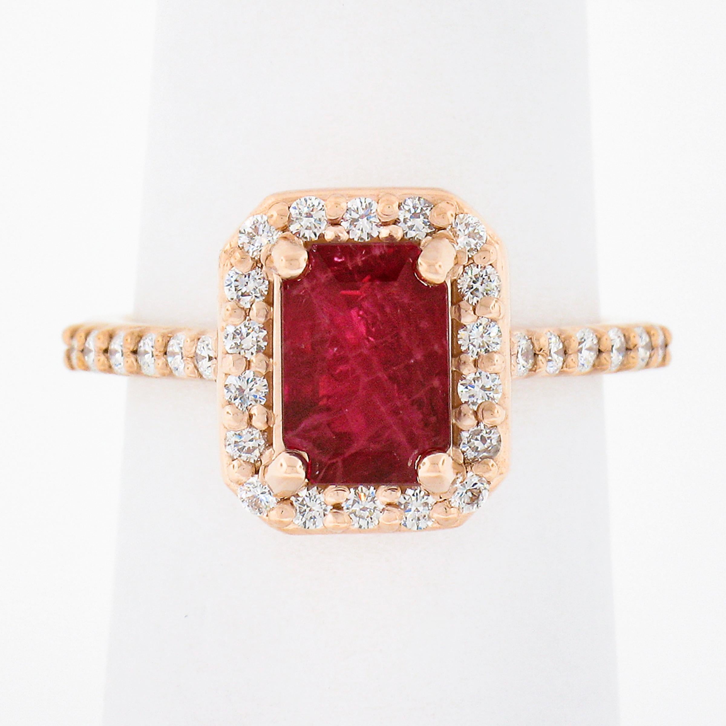 This gorgeous engagement or cocktail style ring is newly crafted in solid 14k rose gold and features a stunning, GIA certified, emerald cut ruby neatly prong set at its center. This center stone is certified as weighing exactly 1.96 carats and