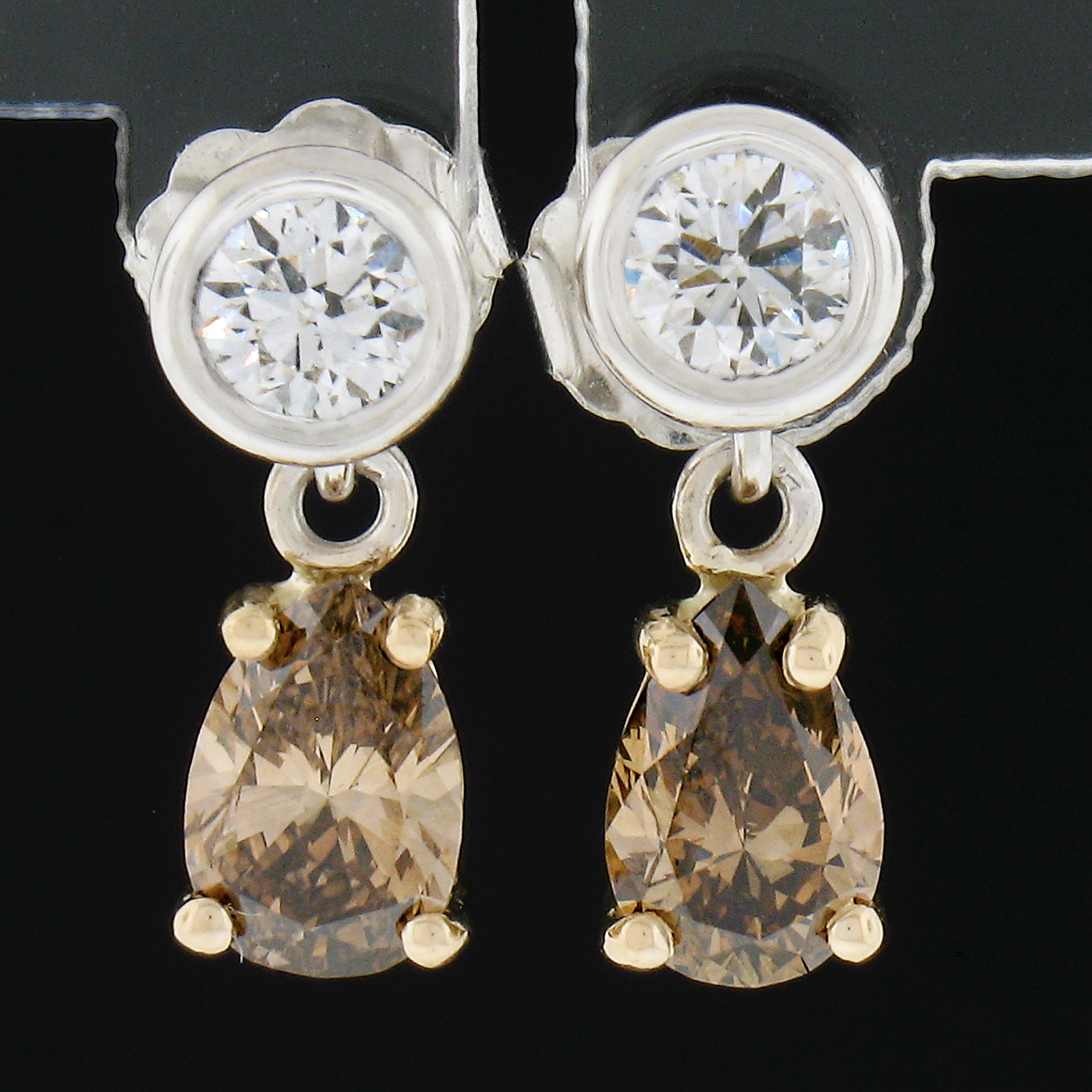 These new drop/dangle elegant earrings are crafted in solid 14k yellow and white gold. They feature 2 round brilliant cut bezel set diamonds and 2 dangling pear cut fancy brown prong set diamonds. These simple yet elegant earrings can be dressed up