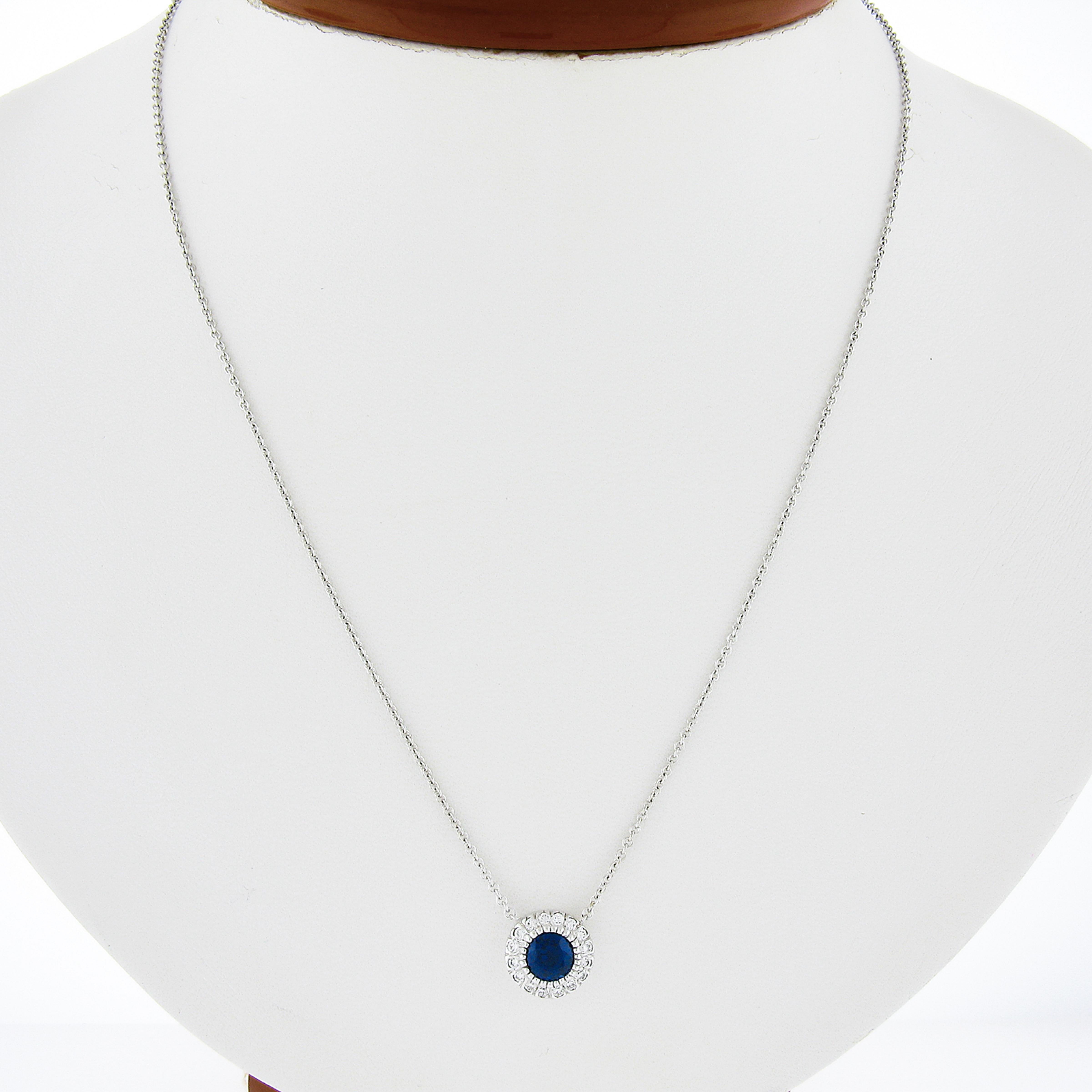 This stunning pendant necklace is newly crafted in solid 14k white gold and features a gorgeous sapphire solitaire neatly multi-prong set at the center of a fine diamond halo. The round brilliant cut sapphire weighs exactly 0.82 carats, and stands