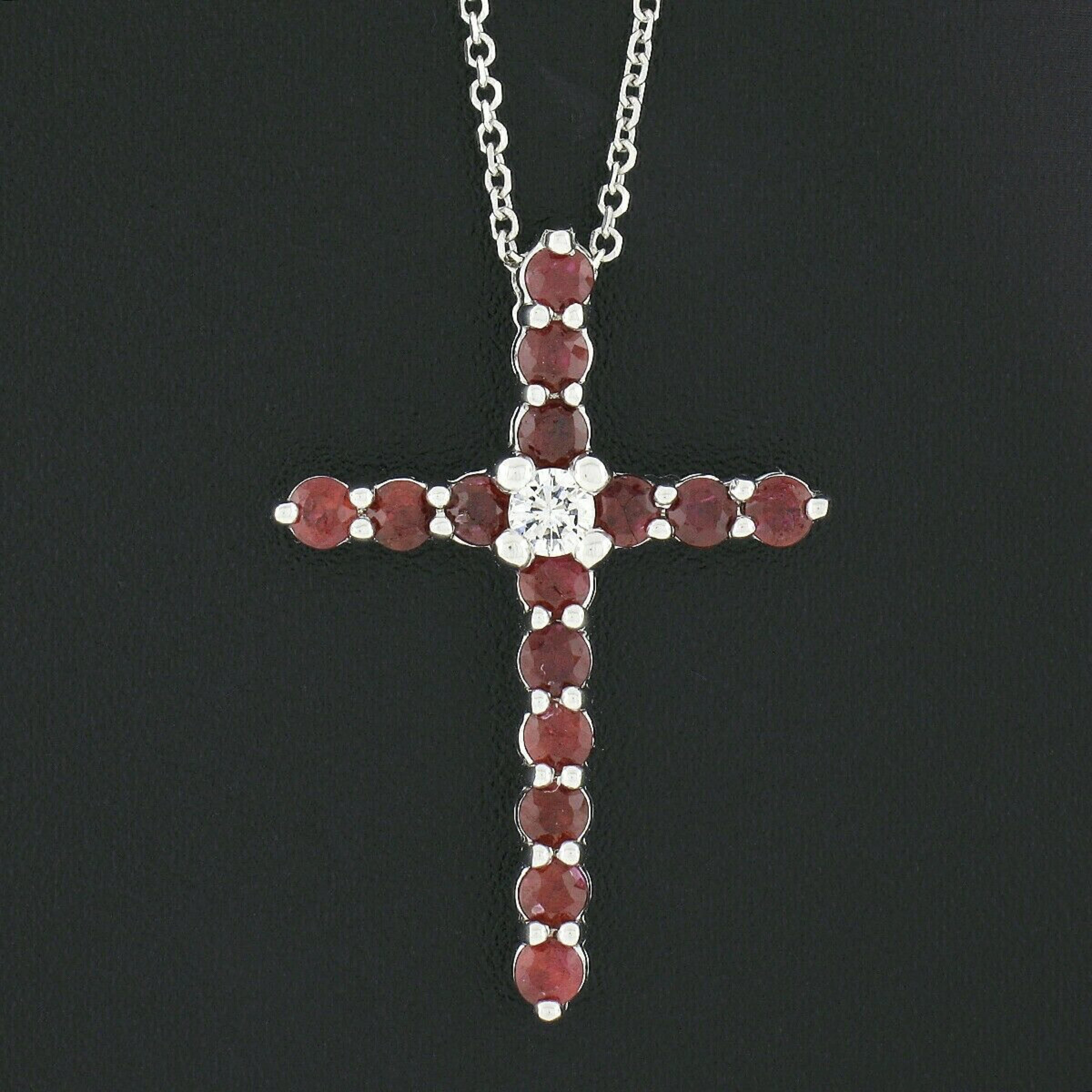Here we have an incredible cross pendant necklace that is newly crafted from solid 14k white gold and is neatly set with gorgeous rubies throughout and a fine diamond at the center. The round brilliant cut rubies show an absolutely stunning deep red