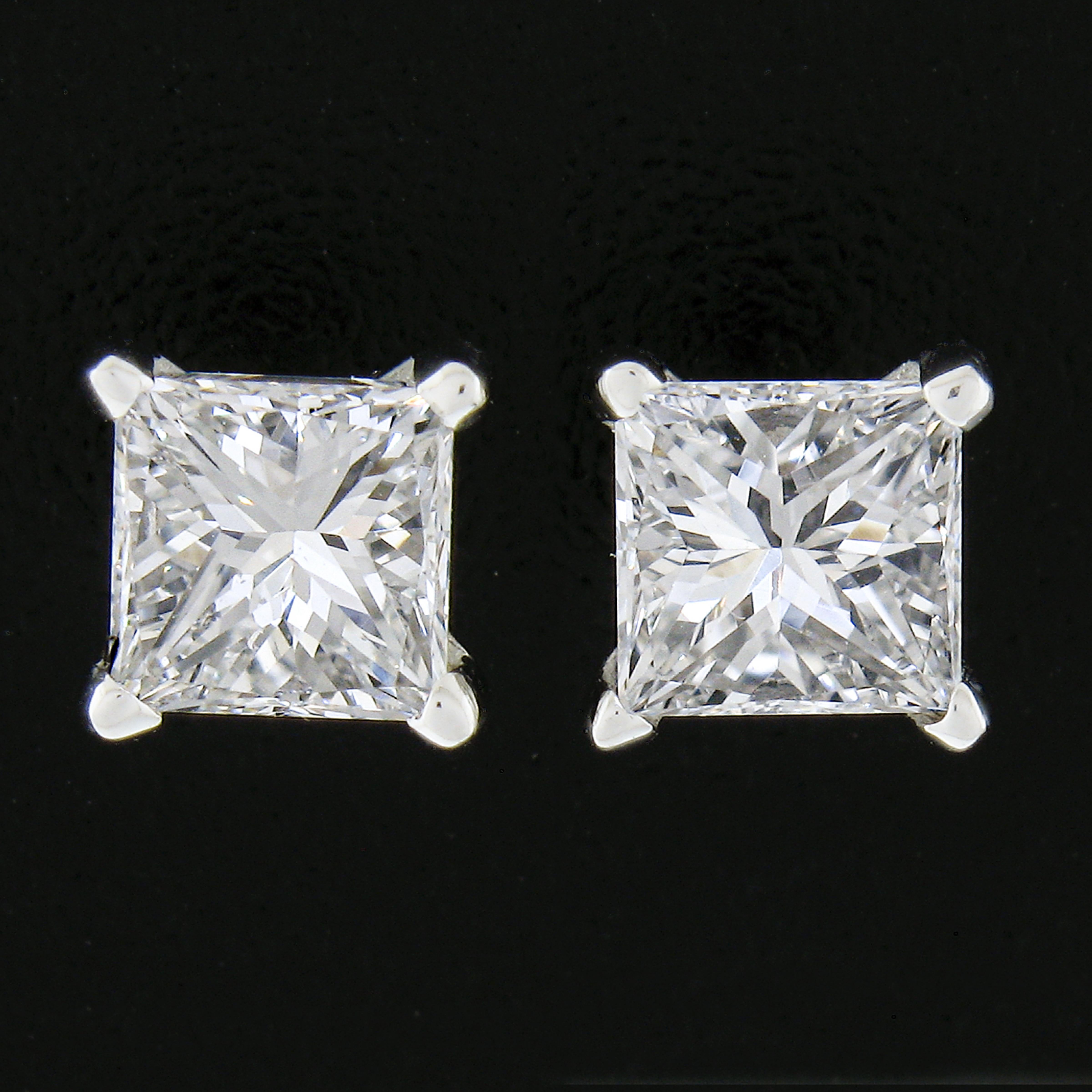 This stunning pair of diamond stud earrings was newly crafted from solid 14k white gold and features two exceptionally brilliant and fiery, princess cut diamonds. The diamonds total exactly 0.82 carats in weight and are very well matched with near