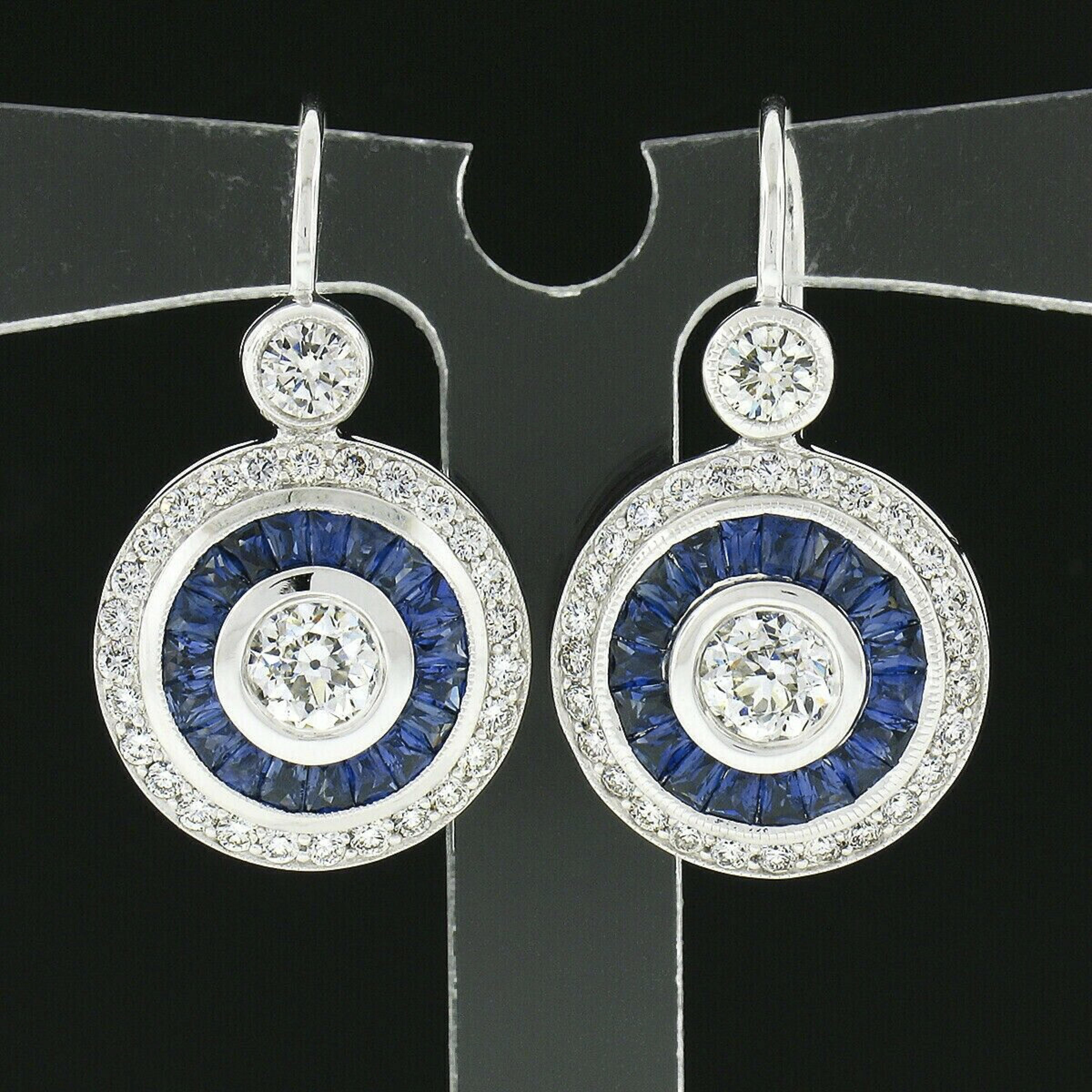This spectacular and very well made pair of drop earrings is newly crafted in solid 14k white gold and feature two antique, old European cut, diamonds that are neatly bezel set at their center and further surrounded by gorgeous natural rubies and