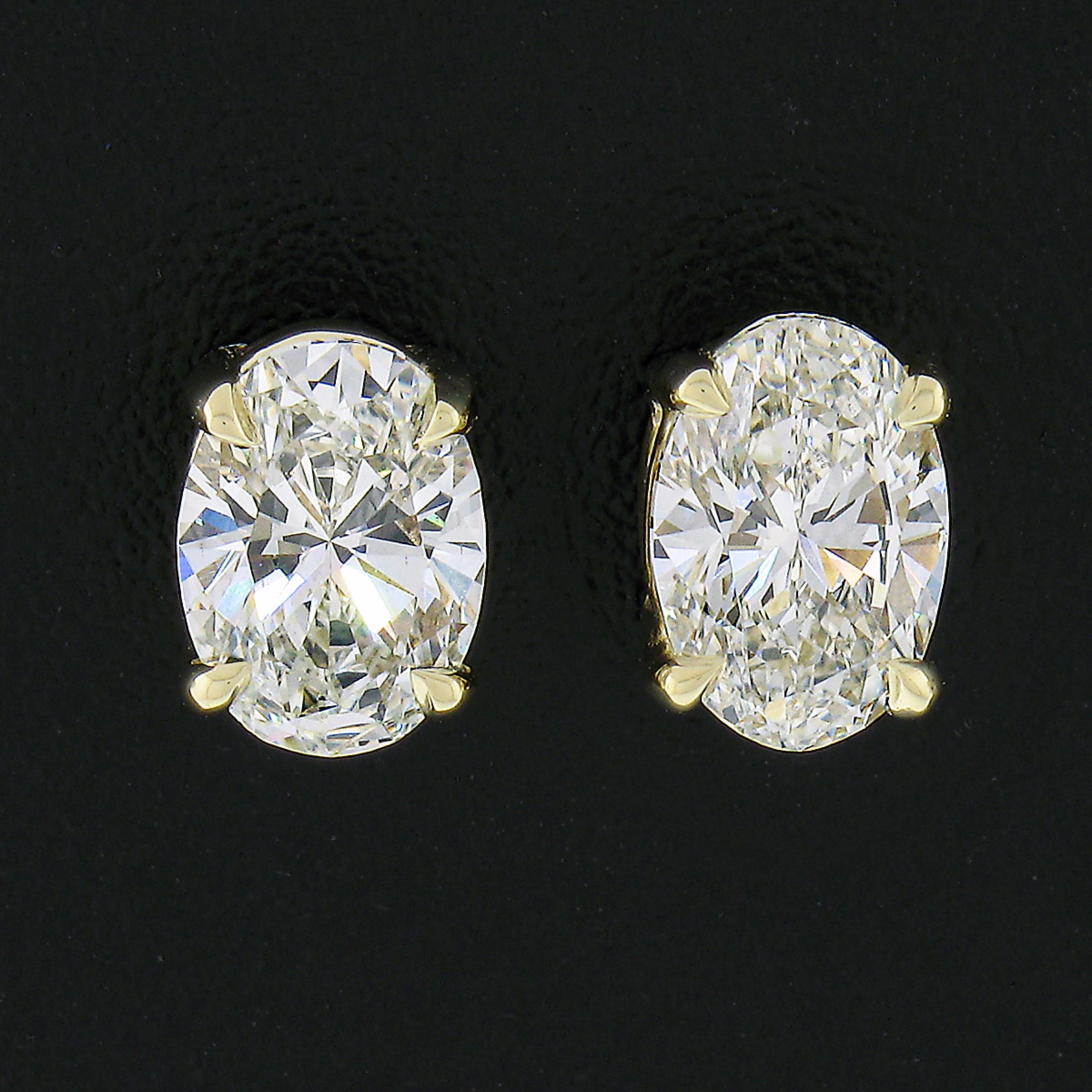 This magnificent pair of diamond stud earrings is newly crafted in solid 14k yellow gold and features two very fine quality oval brilliant cut diamonds. They are both individually GIA certified and total exactly 1.10 carats in weight. The fire and