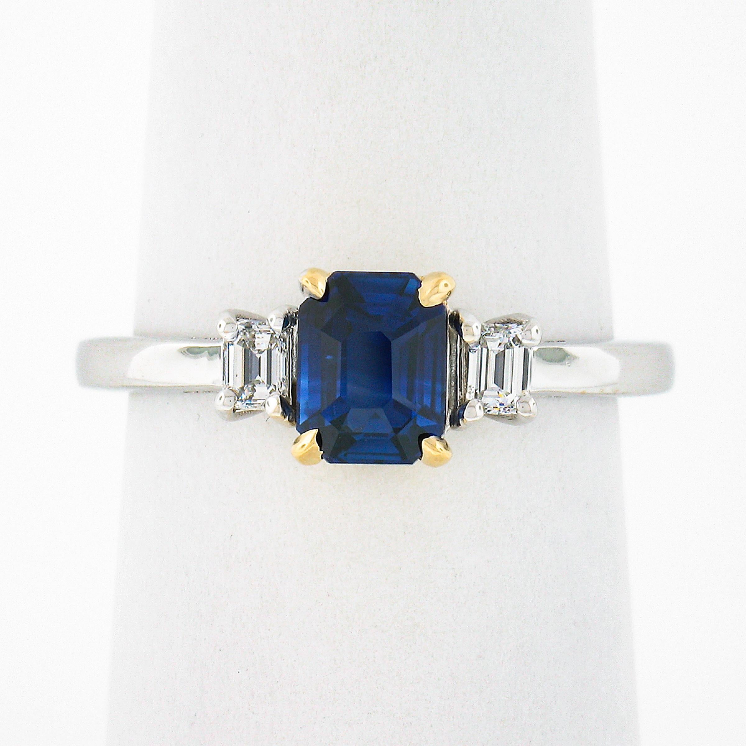 This very elegant sapphire and diamond three stone engagement ring is newly crafted in solid 18k white & yellow gold. It features a gorgeous GIA certified, 1.19 carat emerald cut sapphire solitaire, prong set in the center yellow gold basket and