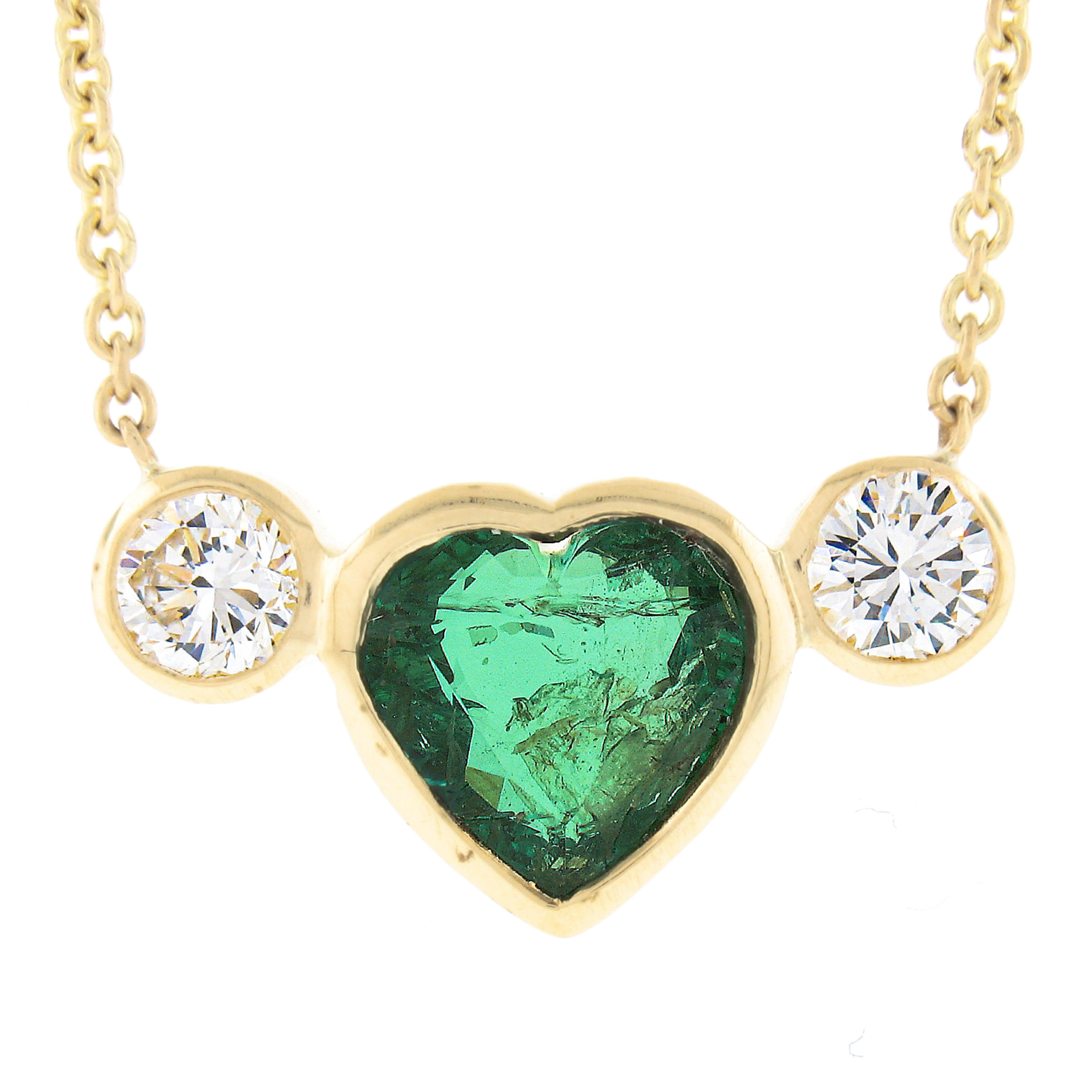 This stunning emerald and diamond pendant is newly crafted in solid 18k yellow gold and features a gorgeous, GIA certified, heart cut genuine emerald stone neatly bezel set at the center heart shaped bezel setting weighing exactly 1.92 carats. This