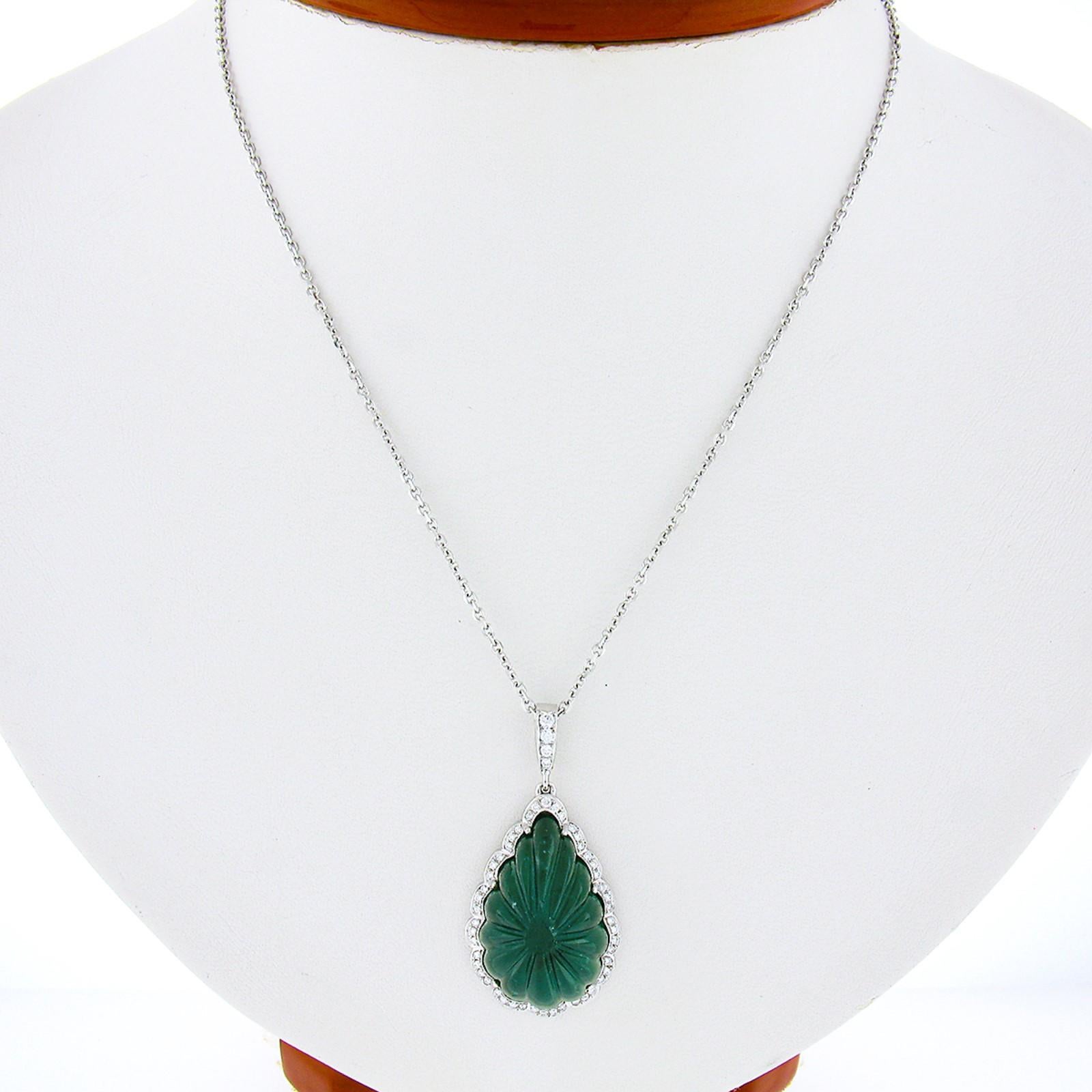 This incredible custom made pendant necklace is newly crafted in solid 18k white gold and features a large pear shape cabochon cut emerald that has been perfectly carved into showing a truly elegant scalloped design throughout. This beautiful stone