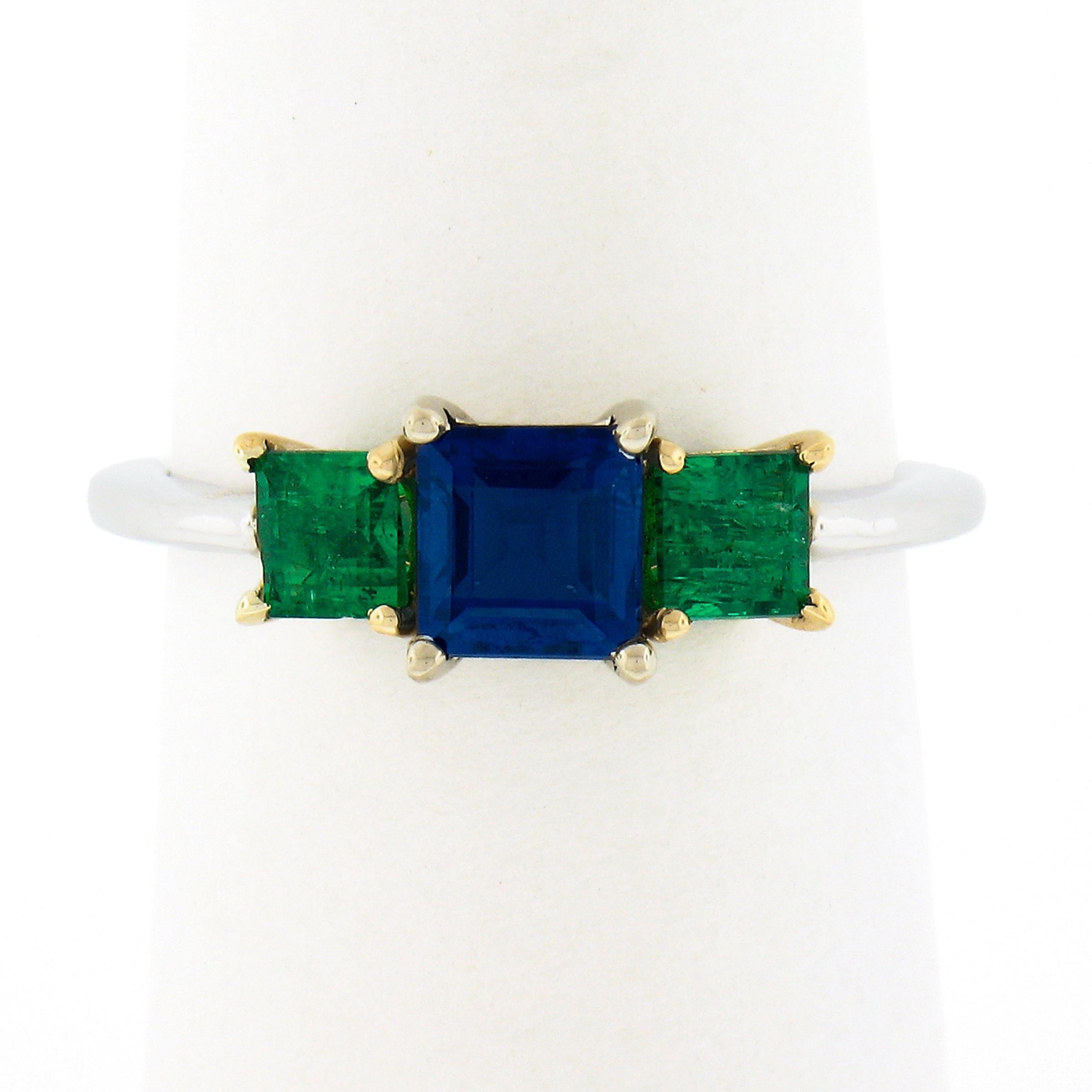 You are looking at an absolutely gorgeous, custom made, sapphire and emerald three stone ring that is newly crafted in solid 18k white gold with yellow gold side basket settings. The ring features a beautiful, GIA certified, square step cut sapphire