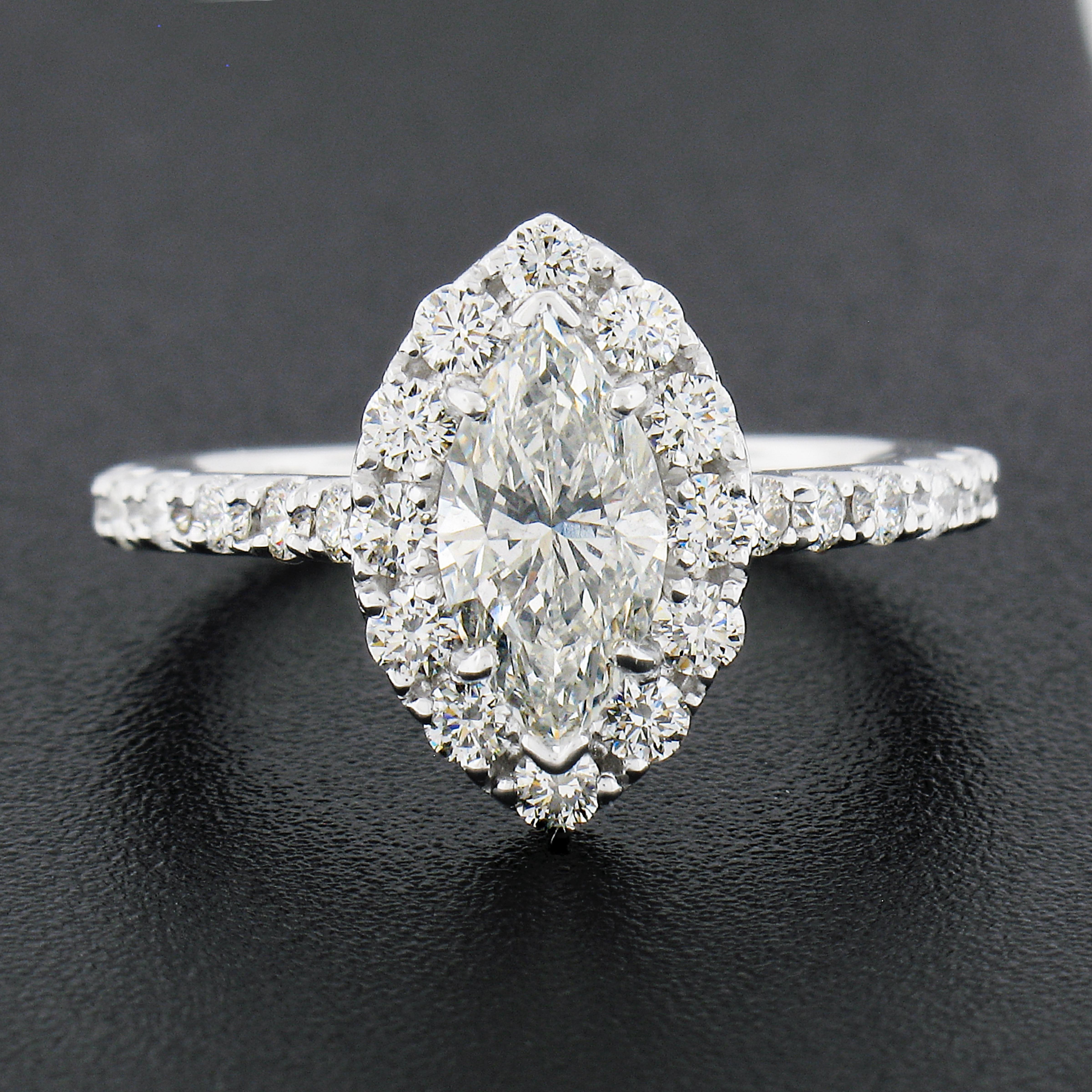 Here we have a gorgeous diamond engagement ring that is newly crafted from solid 18k white gold. The ring features a stunning, GIA certified, marquise cut diamond that is neatly prong set at the center of a fiery round brilliant diamond halo design.