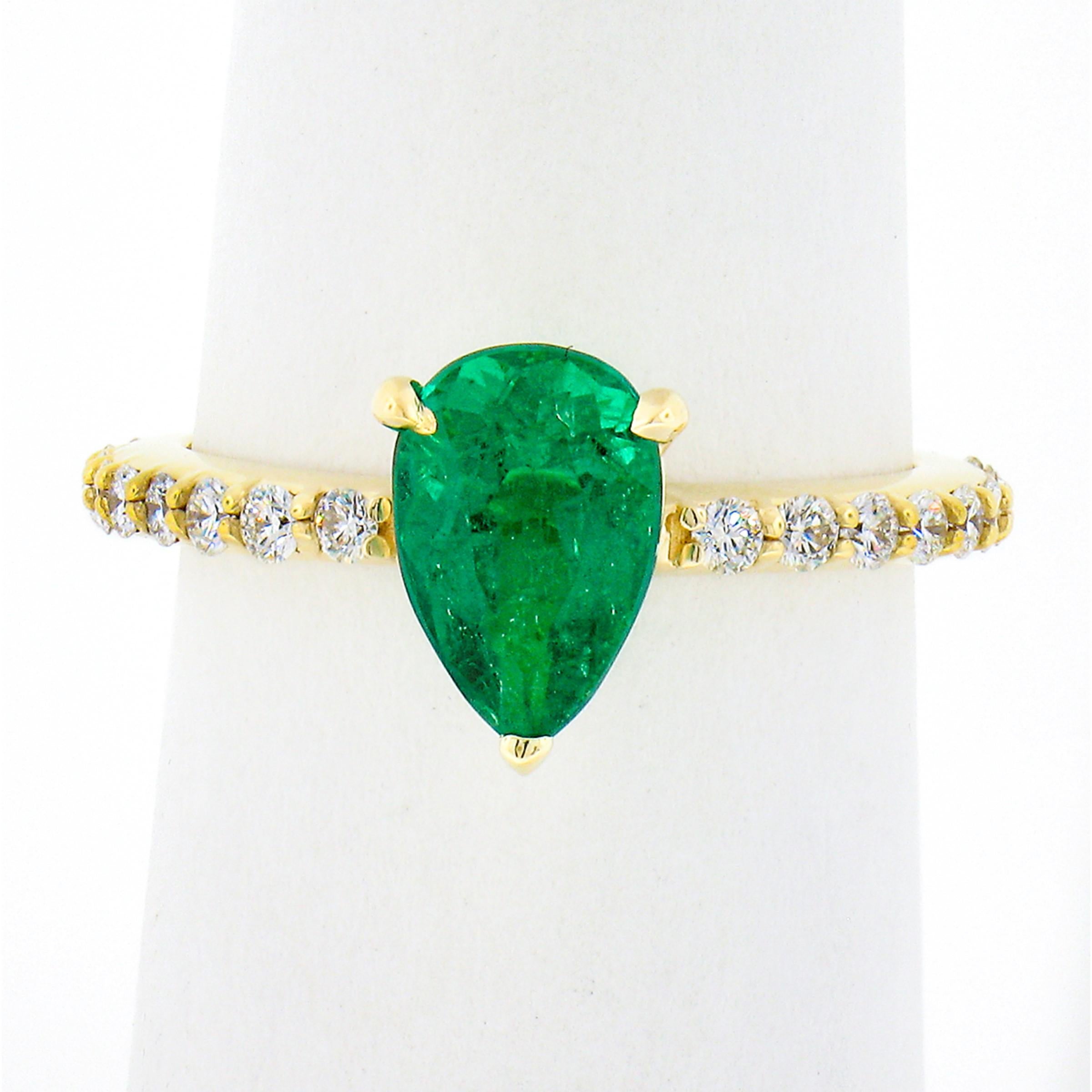 This stunning, SSEF certified, emerald and diamond engagement ring is newly crafted in solid 18k yellow gold. The ring features a breathtaking, natural, pear cut emerald stone that displays the finest and most desirable vivid green color. This very