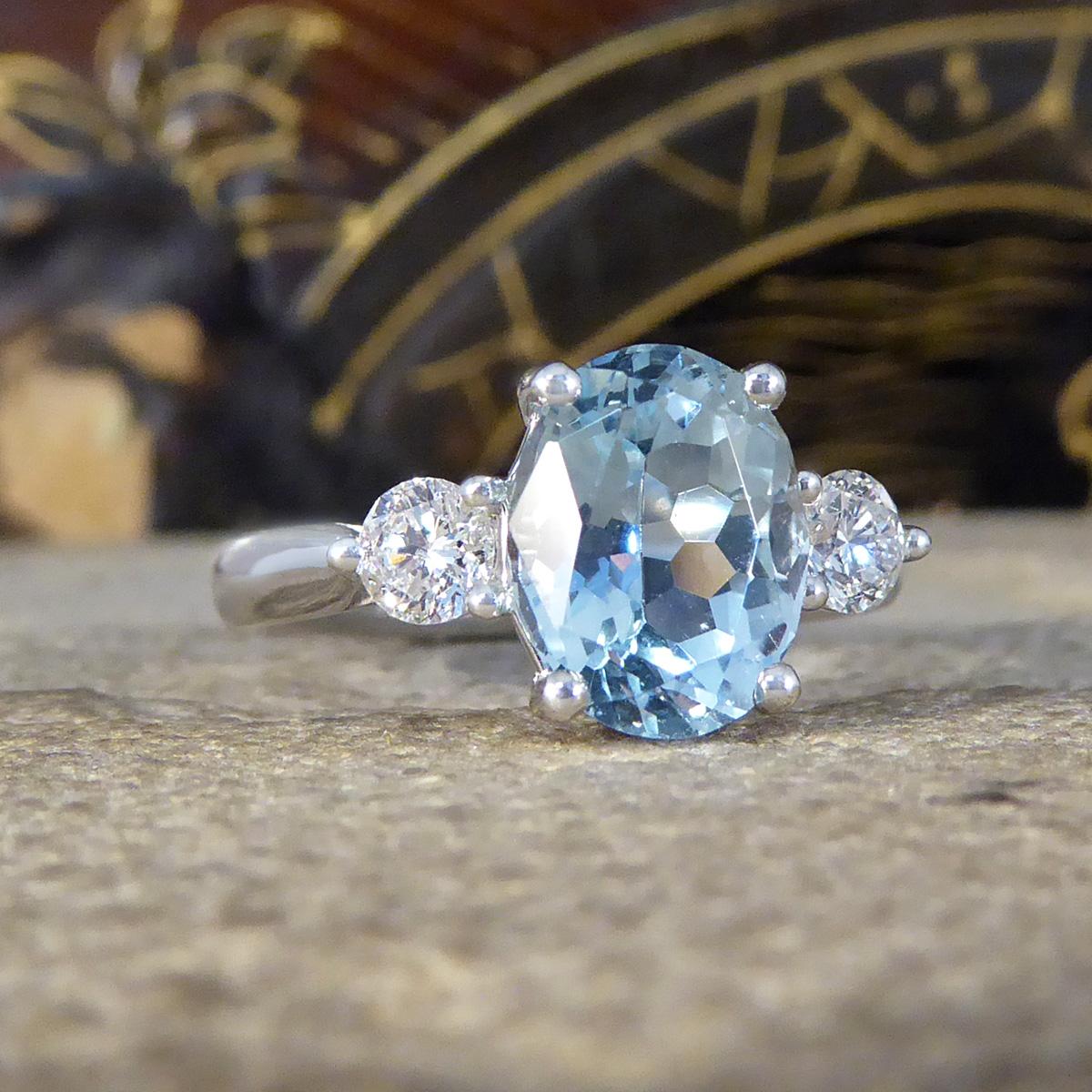 An absolutely gorgeous and sparkly Aquamarine and Diamond three stone ring that holds three beautiful stones set in secure claw settings. In the centre sits a lovely bright Oval Cut Aquamarine with a light blue colour to it weighing 1.93ct with a