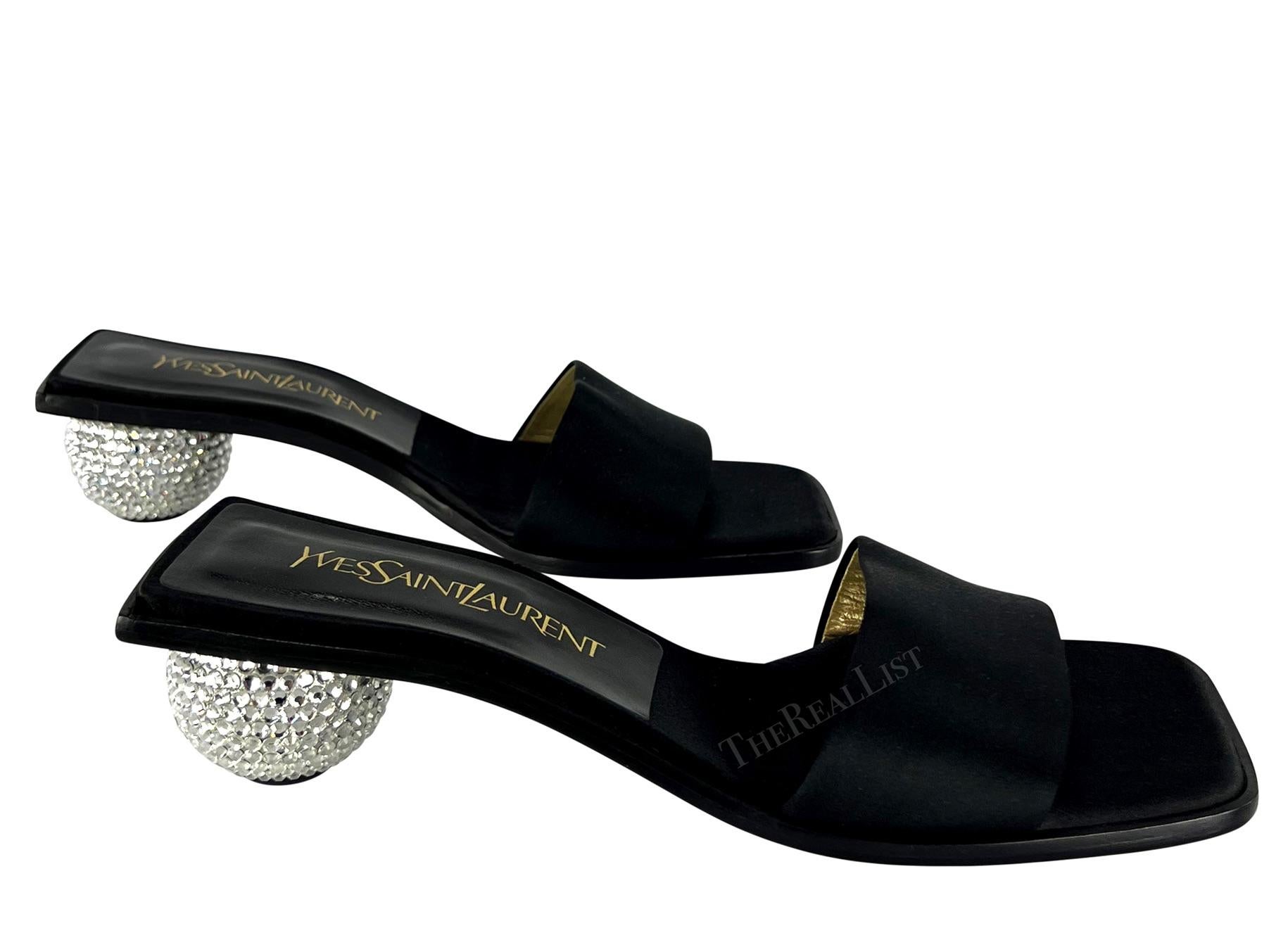 Presenting a pair of black satin Yves Saint Laurent heeled sandals. From the early 1990s, these chic never worn before sandals are amped up with round rhinestone embellished heels. Add these rare disco ball Yves Saint Laurent sandals to your