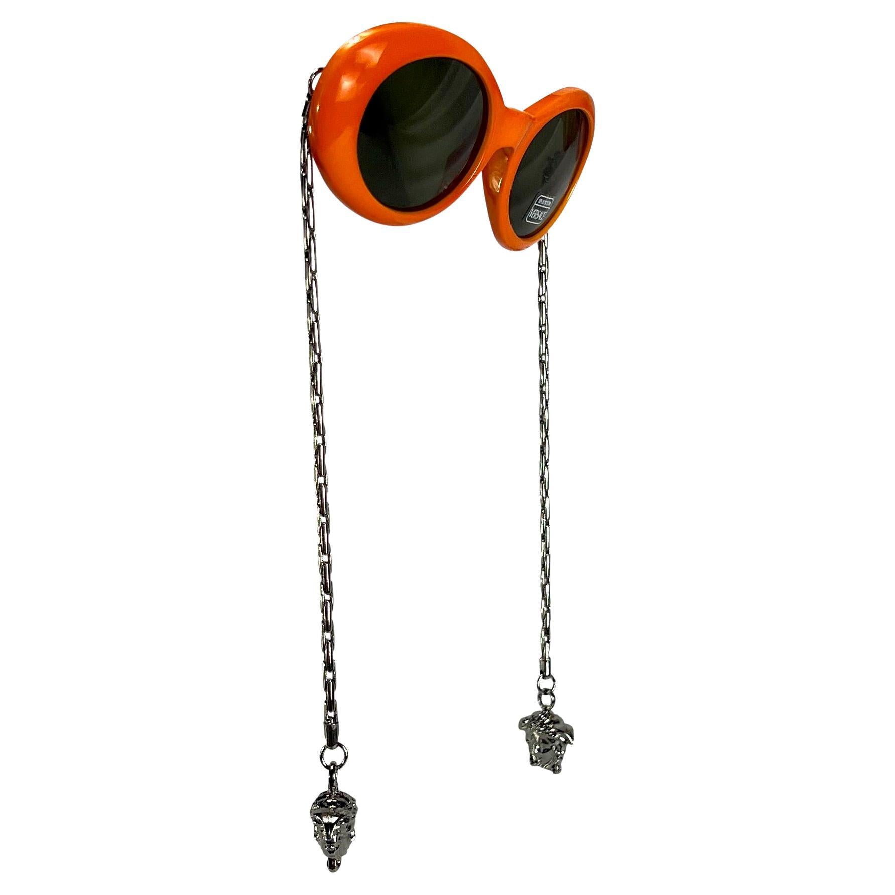 Presenting a fabulous pair of vibrant orange round silver tone chain arm Gianni Versace sunglasses, designed by Gianni Versace. These ultra-rare sunglasses from 1996 feature the famous colorful round mod Versace style and are elevated with